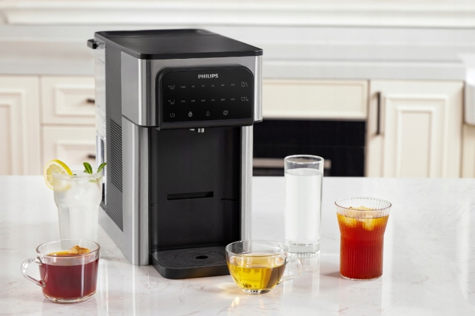 Dystrybutor Philips z napojami, w tym herbatą, sokiem i wodą, na marmurowym blacie.
