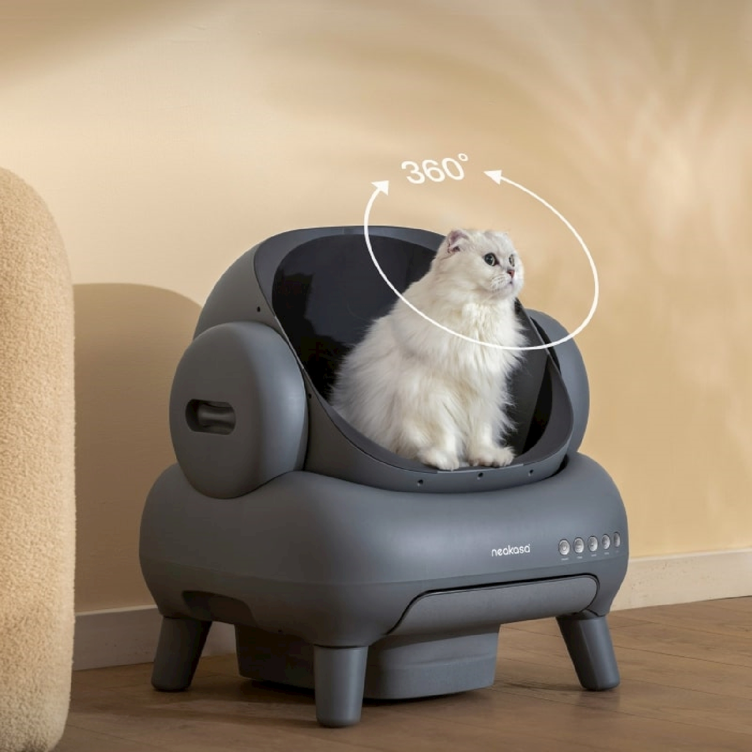 Un gatto bianco è seduto in una lettiera automatica grigia con una grafica di rotazione a 360 gradi.