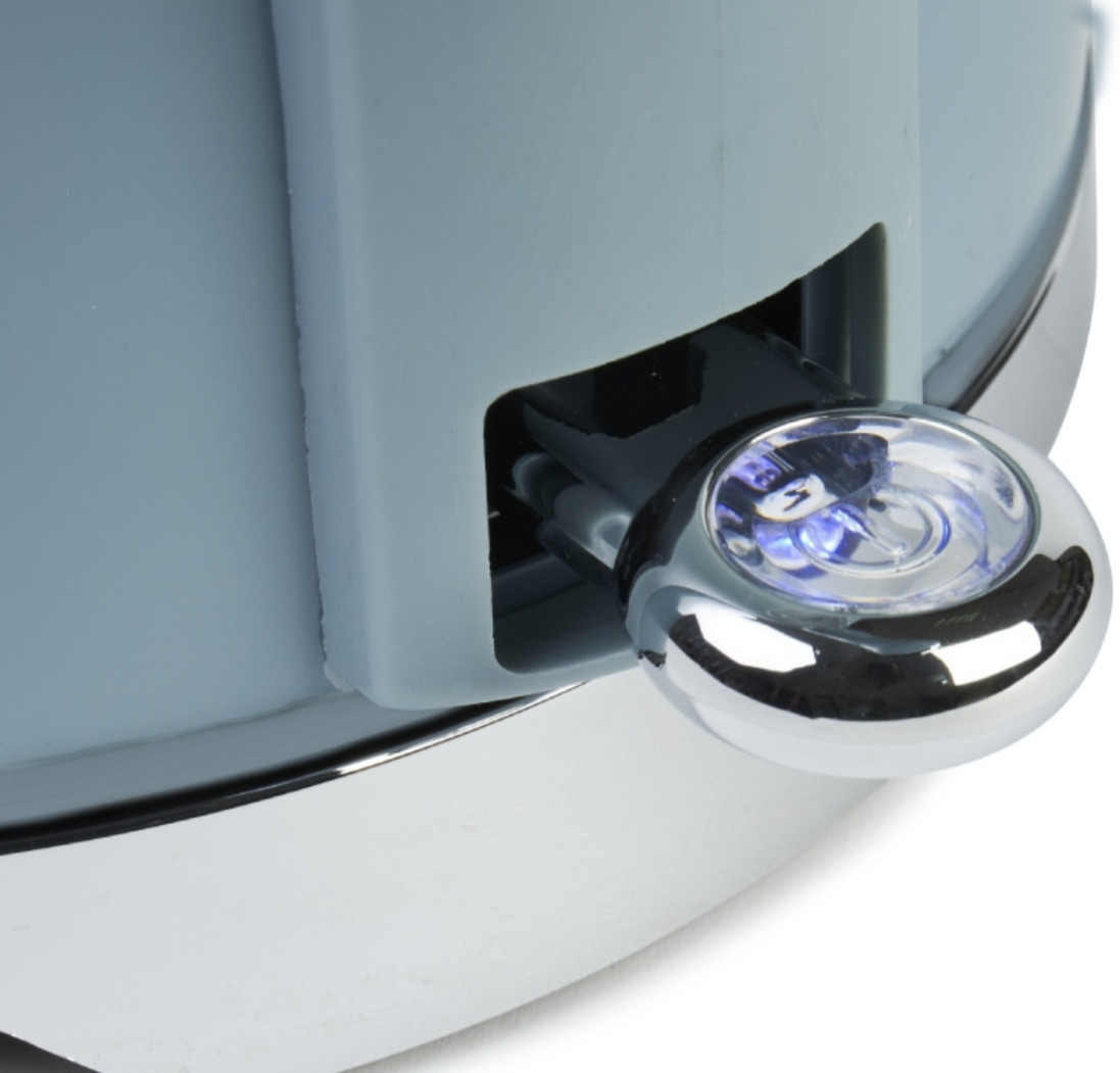 Zbliżenie na przełącznik niebieskiego czajnika Haden. Świeci niebieskie światło.