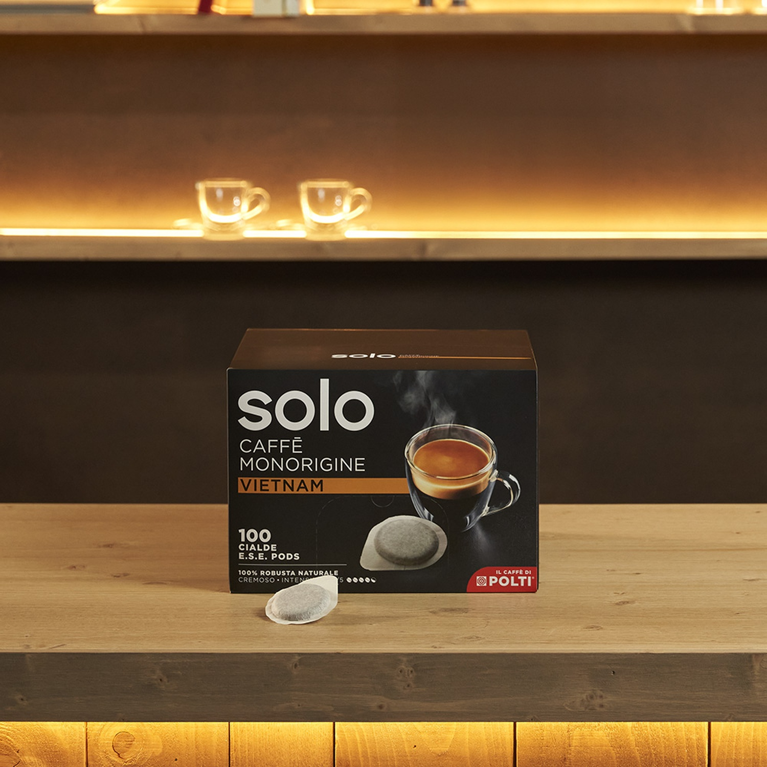 Scatola di cialde di caffè su una superficie di legno. Due piccole tazze sullo sfondo.