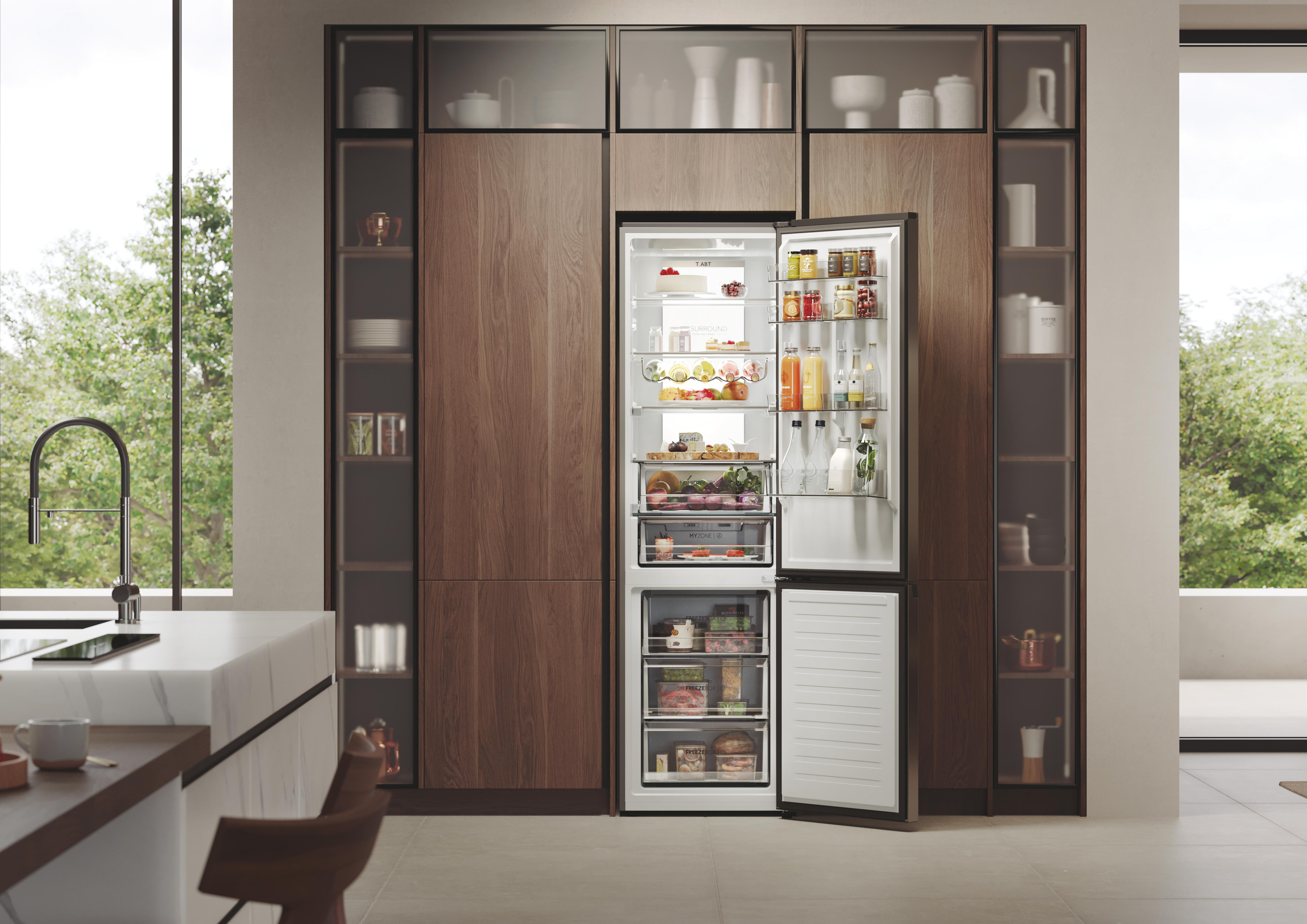 Offener Kühlschrank in einer Küche mit Lebensmitteln. Holzschränke und Fenster links. Bäume sind draußen sichtbar.