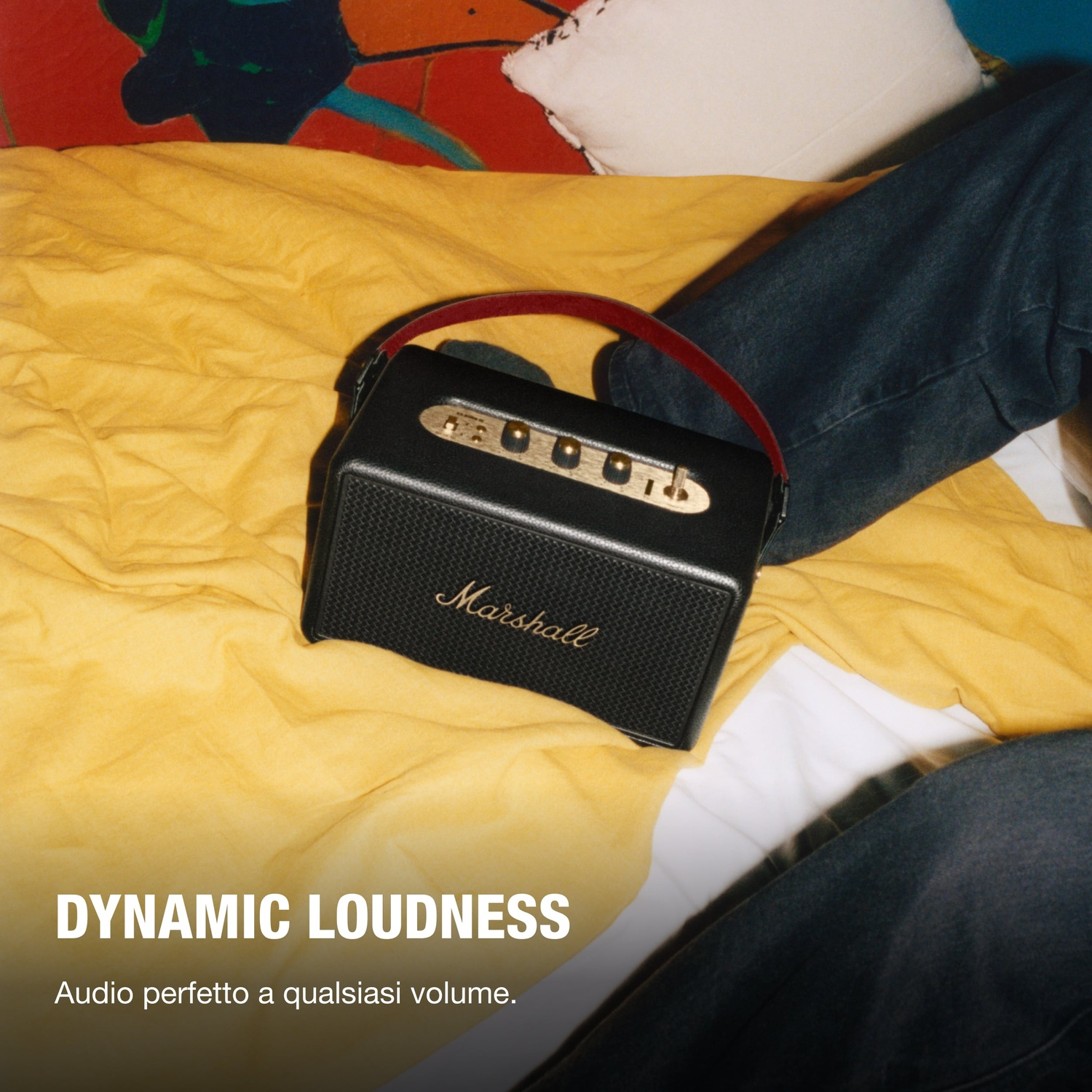 Gambe di una persona e altoparlante Marshall su coperta gialla, con testo 'DYNAMIC LOUDNESS'.