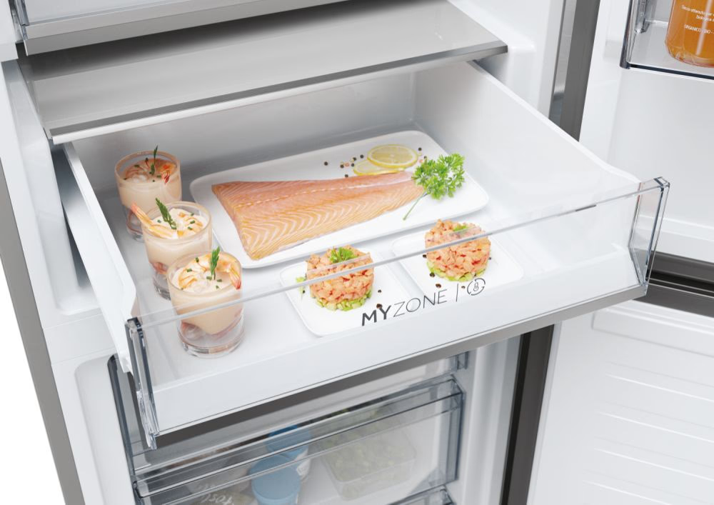 Kühlschublade mit zubereiteten Speisen: Garnelen-Cocktails, Lachs und Ceviche auf weißen Tellern. Eine Zitrone und Petersilie.