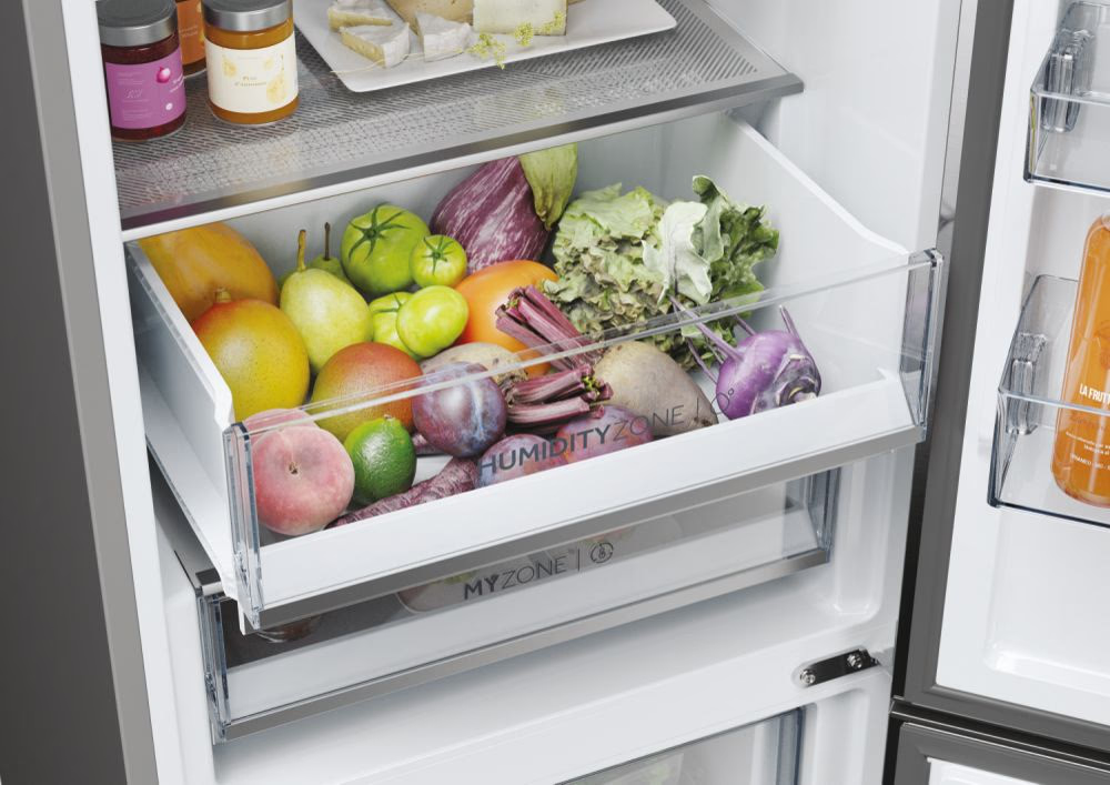 Kühlschublade mit frischen Produkten: Mangos, Birnen, Tomaten, Rüben, Pflaumen und Salat. Als Feuchtigkeitszone gekennzeichnet.
