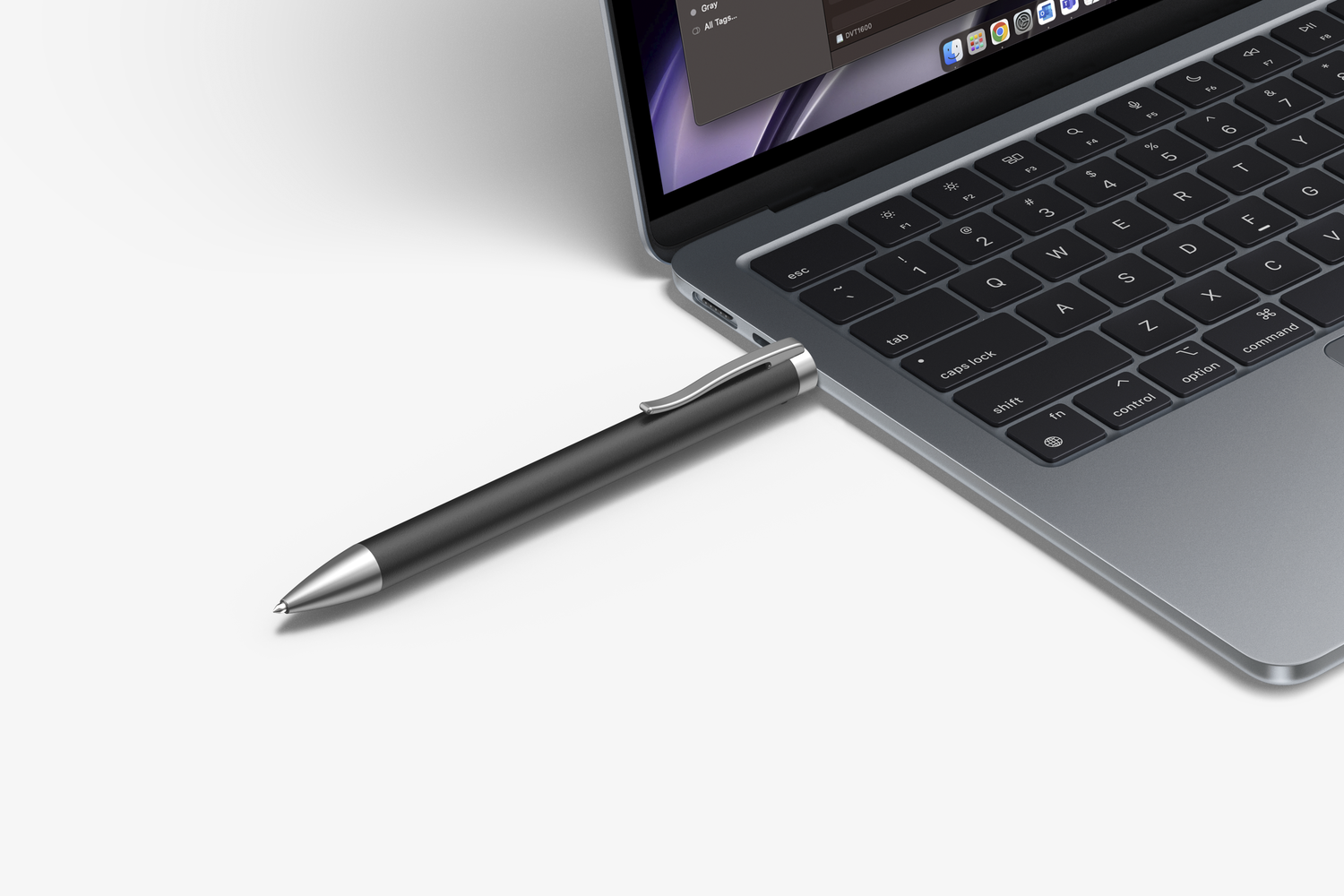 Rysik podłączony do laptopa na białej powierzchni. Pióro jest srebrne i czarne.