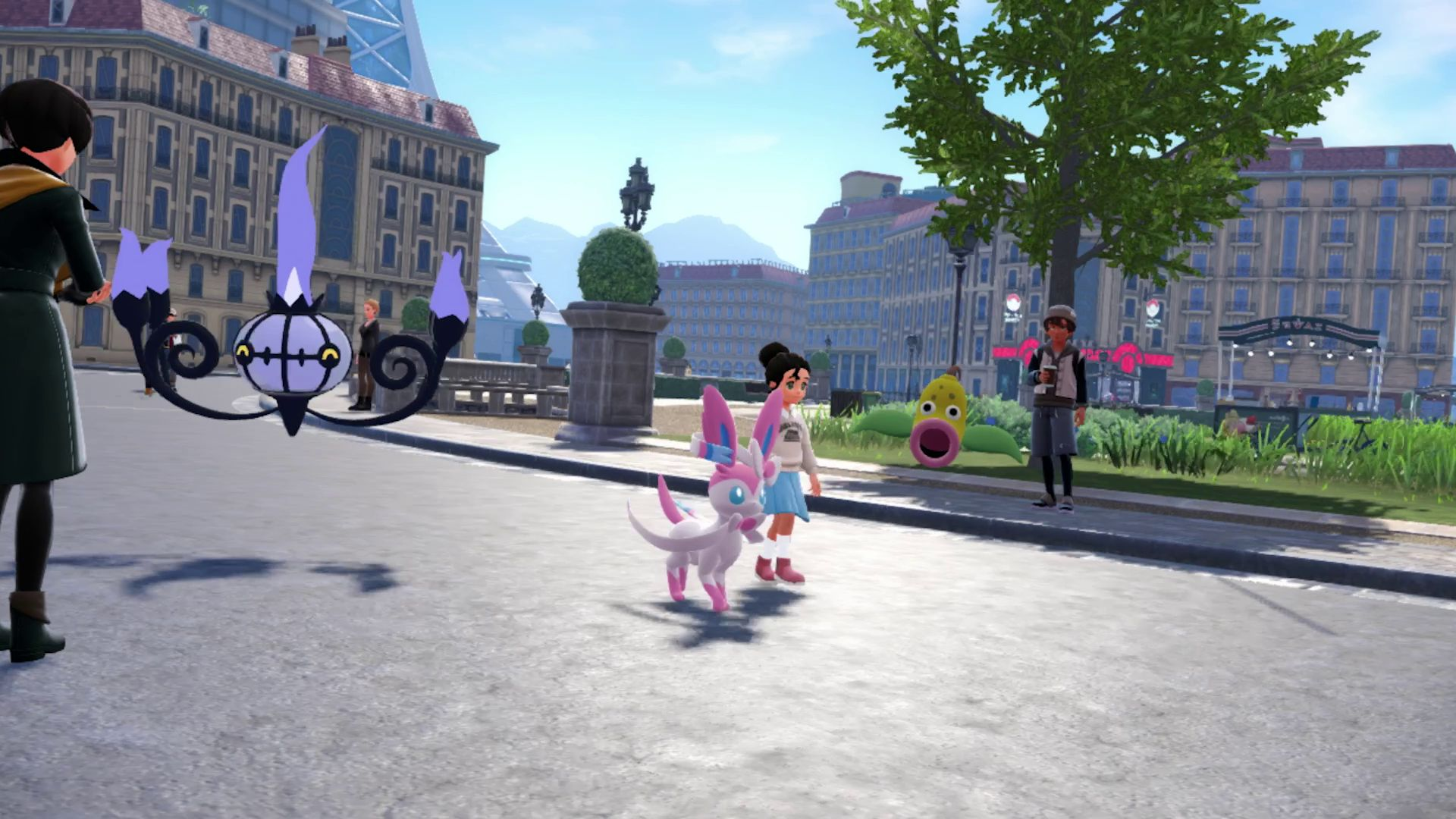 Une scène de ville avec des personnages Pokémon. Un Chandelure flotte. Un Sylveon et une fille marchent. Une personne est avec un café.