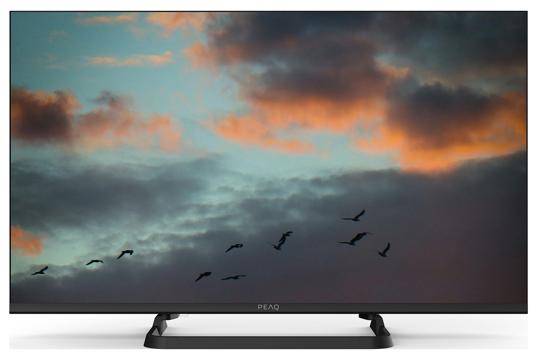 Telewizor wyświetla zachód słońca z przelatującymi ptakami. Niebo ma odcienie pomarańczowego, niebieskiego i szarego. Telewizor ma czarną ramę i podstawę.