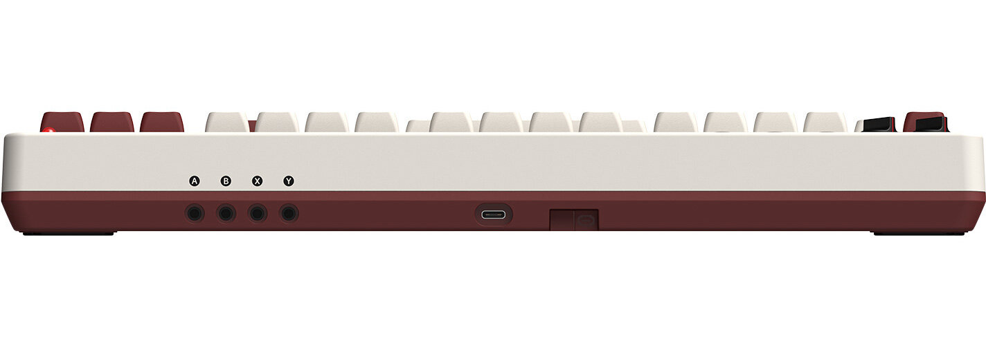 Widok z boku klawiatury retro. Bordowe klawisze, biała rama. Widoczne porty i wskaźniki.