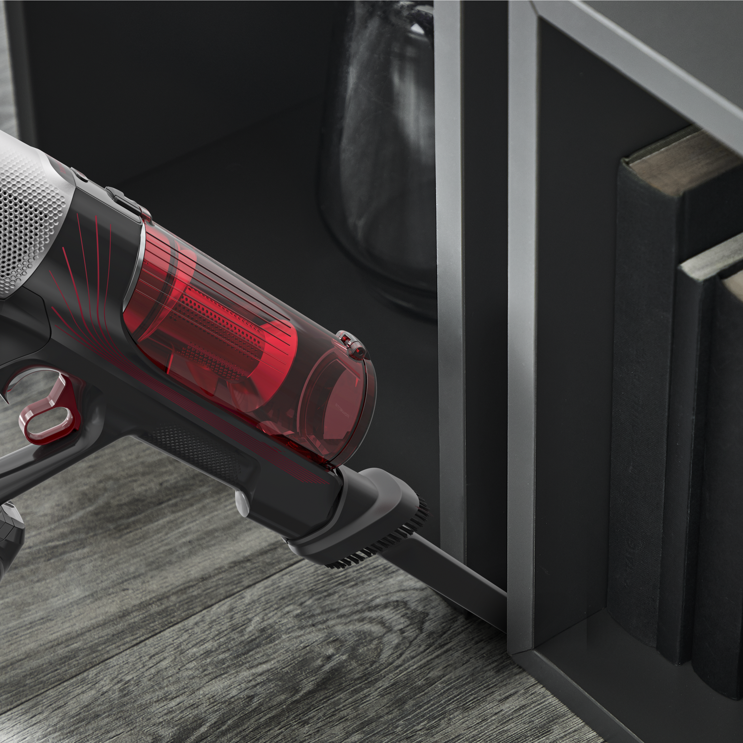 Widok z bliska na głowicę odkurzacza czyszczącą. W kadrze półka na książki i drewniana podłoga.