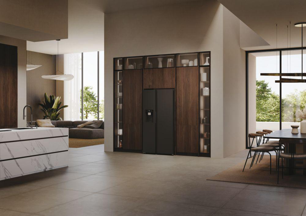 Eine moderne Küche mit einem großen Kühlschrank vor einer dunklen, holzgetäfelten Wand.
