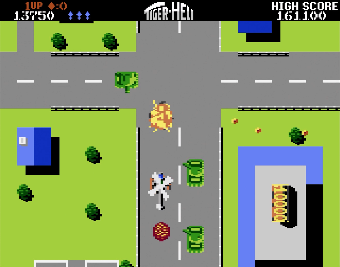 Scène de jeu rétro : Hélicoptère tirant dans une ville. La scène comprend des bâtiments, des espaces verts et des routes.