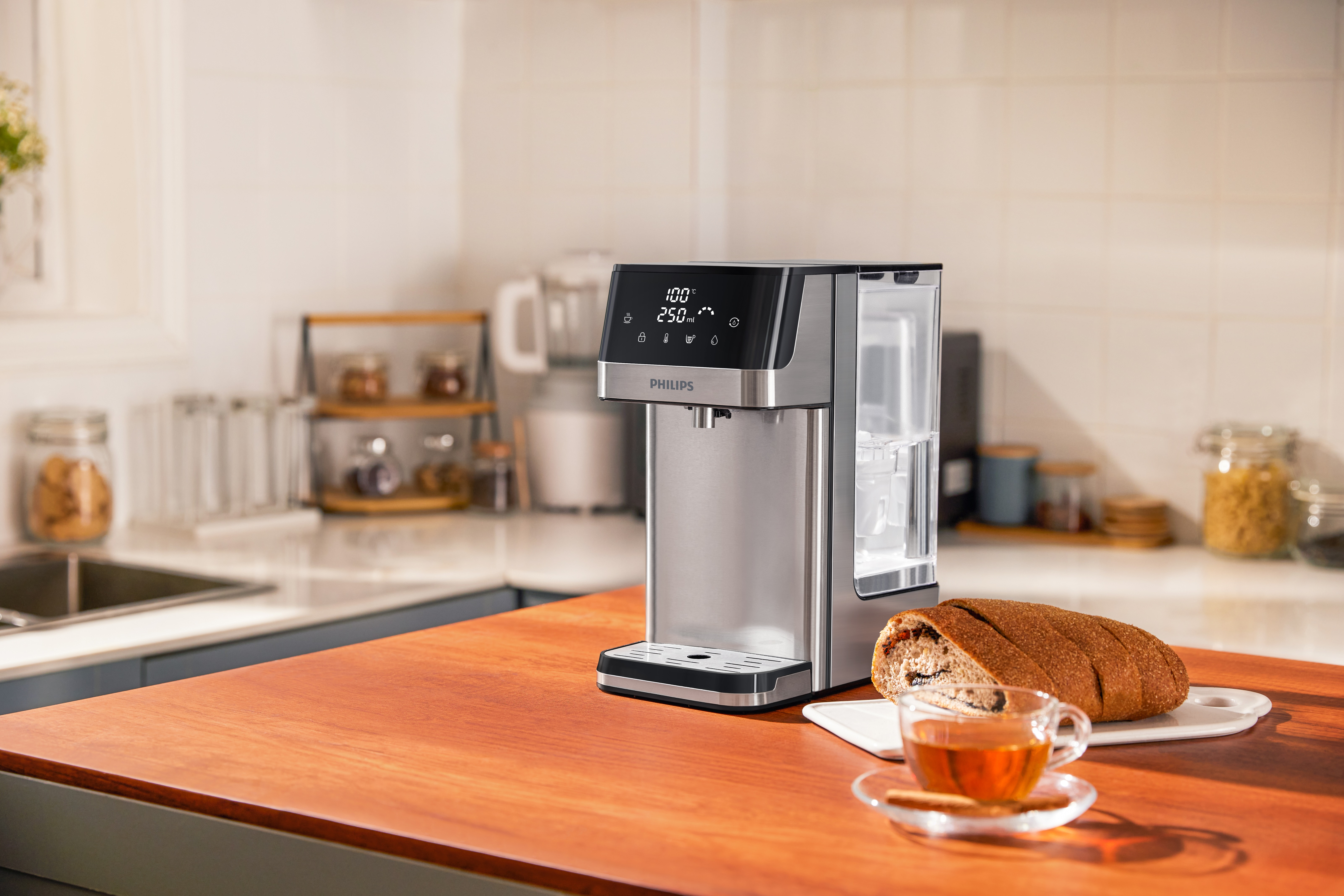 Srebrny czajnik z wyświetlaczem na drewnianym stole z chlebem i filiżanką herbaty.