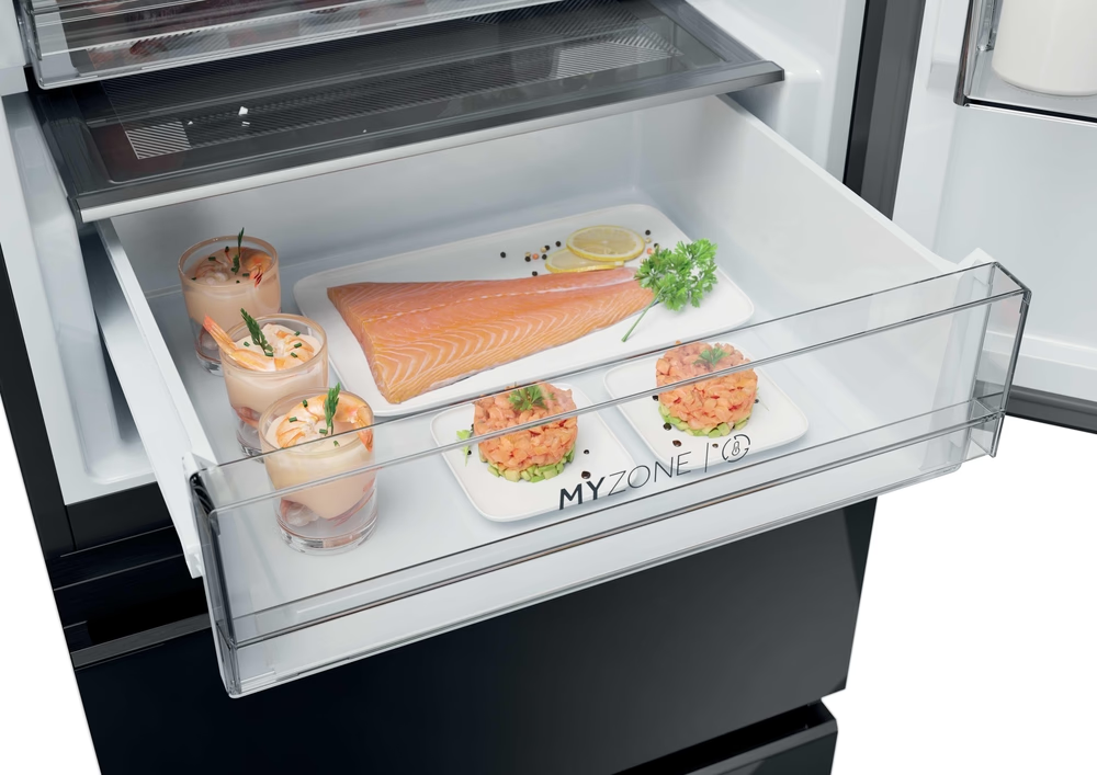 Nahaufnahme einer Kühlschublade mit Shrimp-Cocktails und Lachsgerichten auf weißen Tellern.