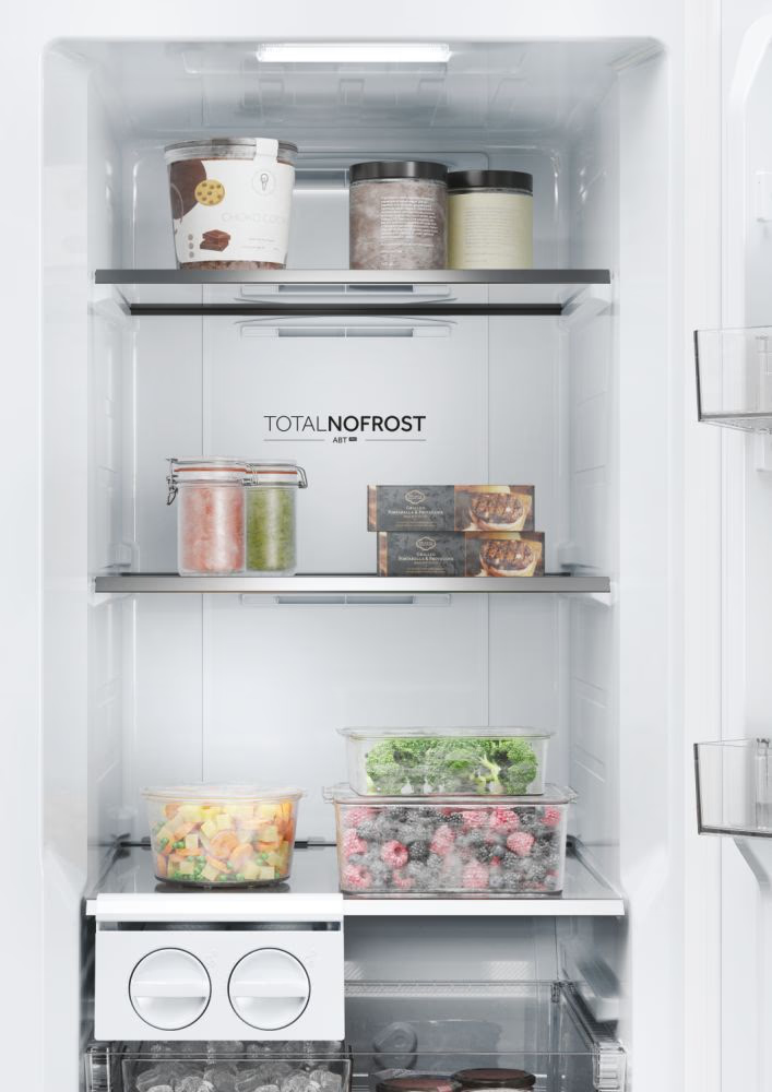 Intérieur de réfrigérateur ouvert avec étagères. Divers aliments sont stockés sur les étagères.