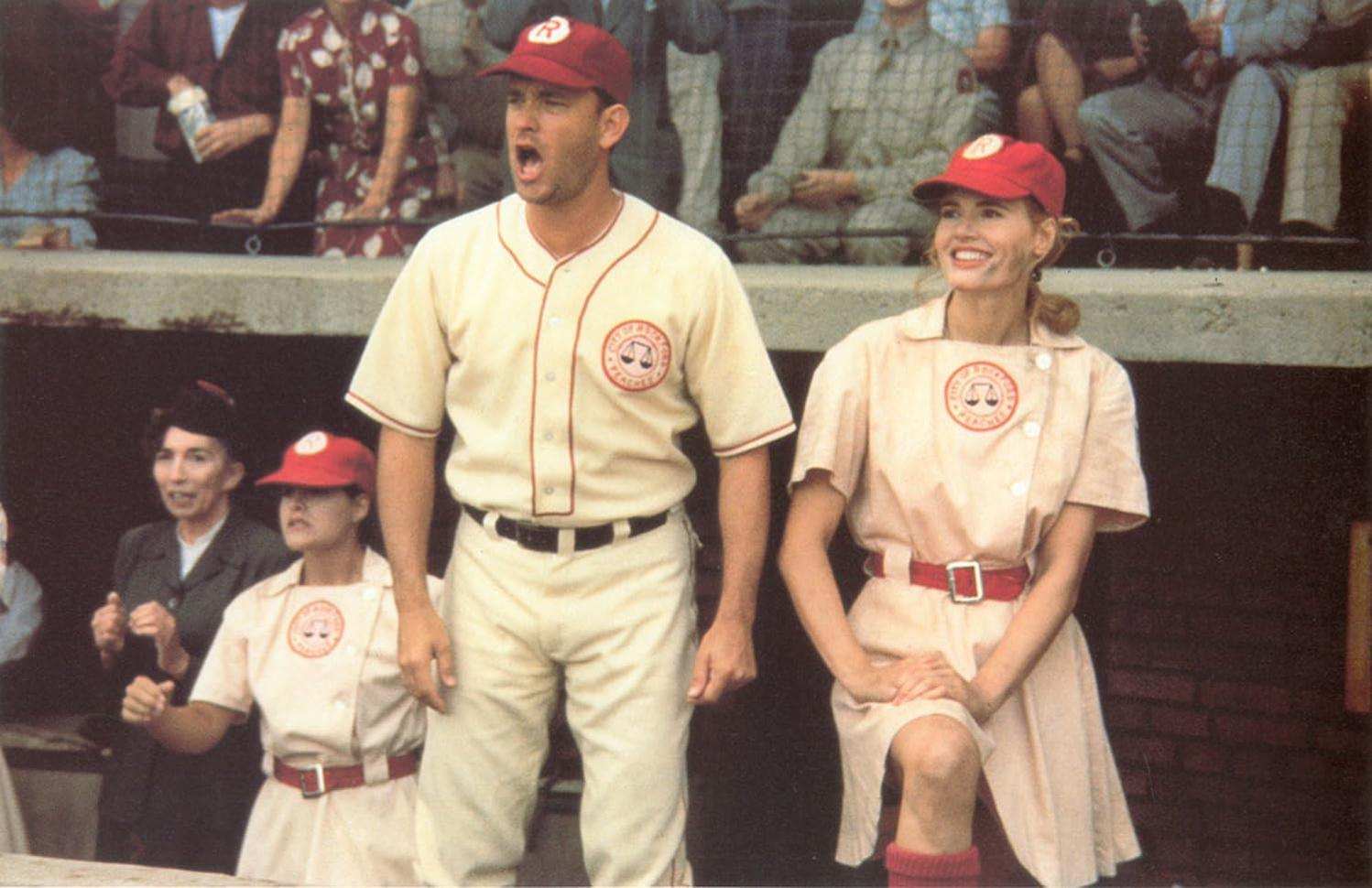 Drei Baseballspieler in Uniformen, mit Tom Hanks, stehen im Dugout.