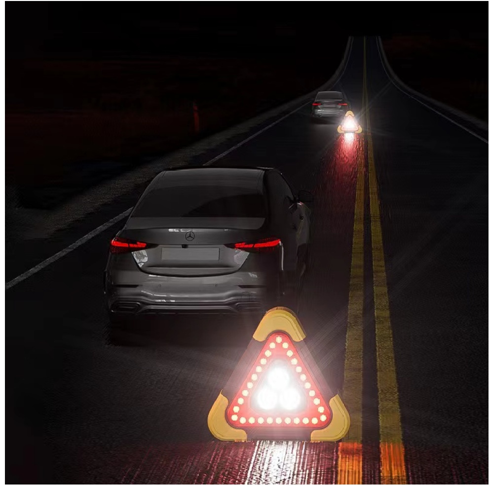 Trójkąty ostrzegawcze na drodze w nocy, z samochodami i światłami.