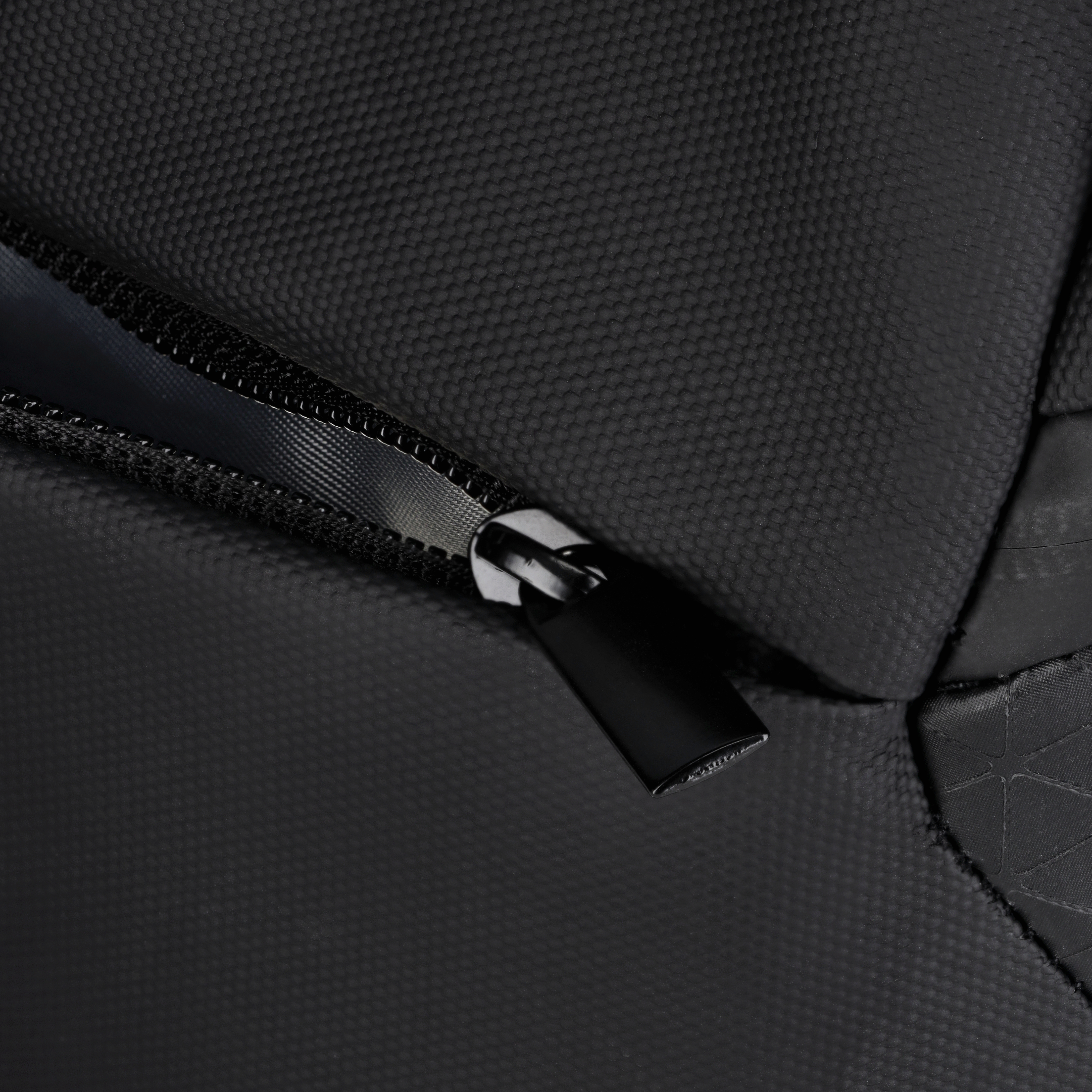 Schwarzes Taschen-Detail, Reißverschluss-Nahaufnahme. Schwarzer Stoff, weißer Hintergrund.