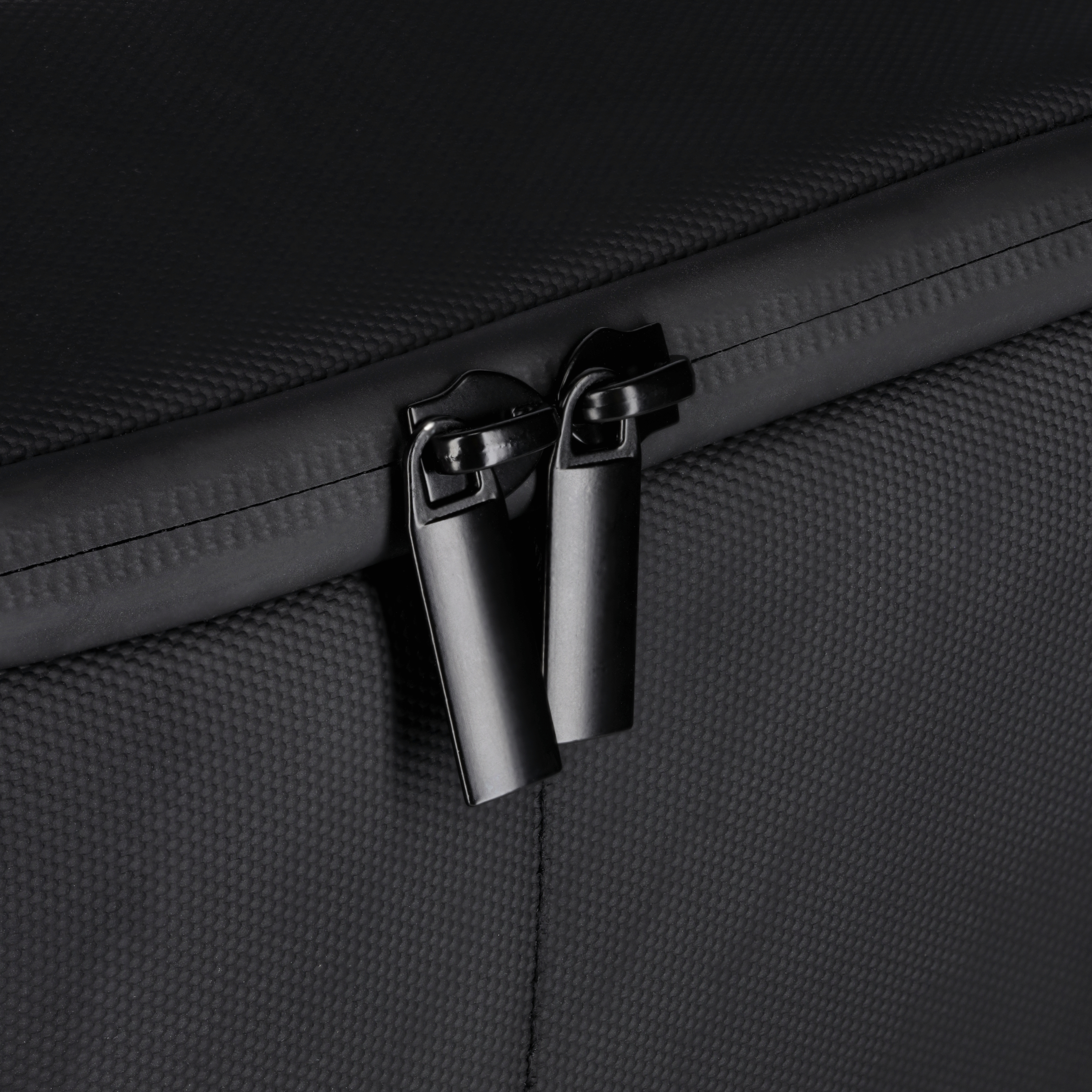 Schwarzes Taschen-Detail, Nahaufnahme von zwei Reißverschlüssen. Schwarzer Stoff, weißer Hintergrund.
