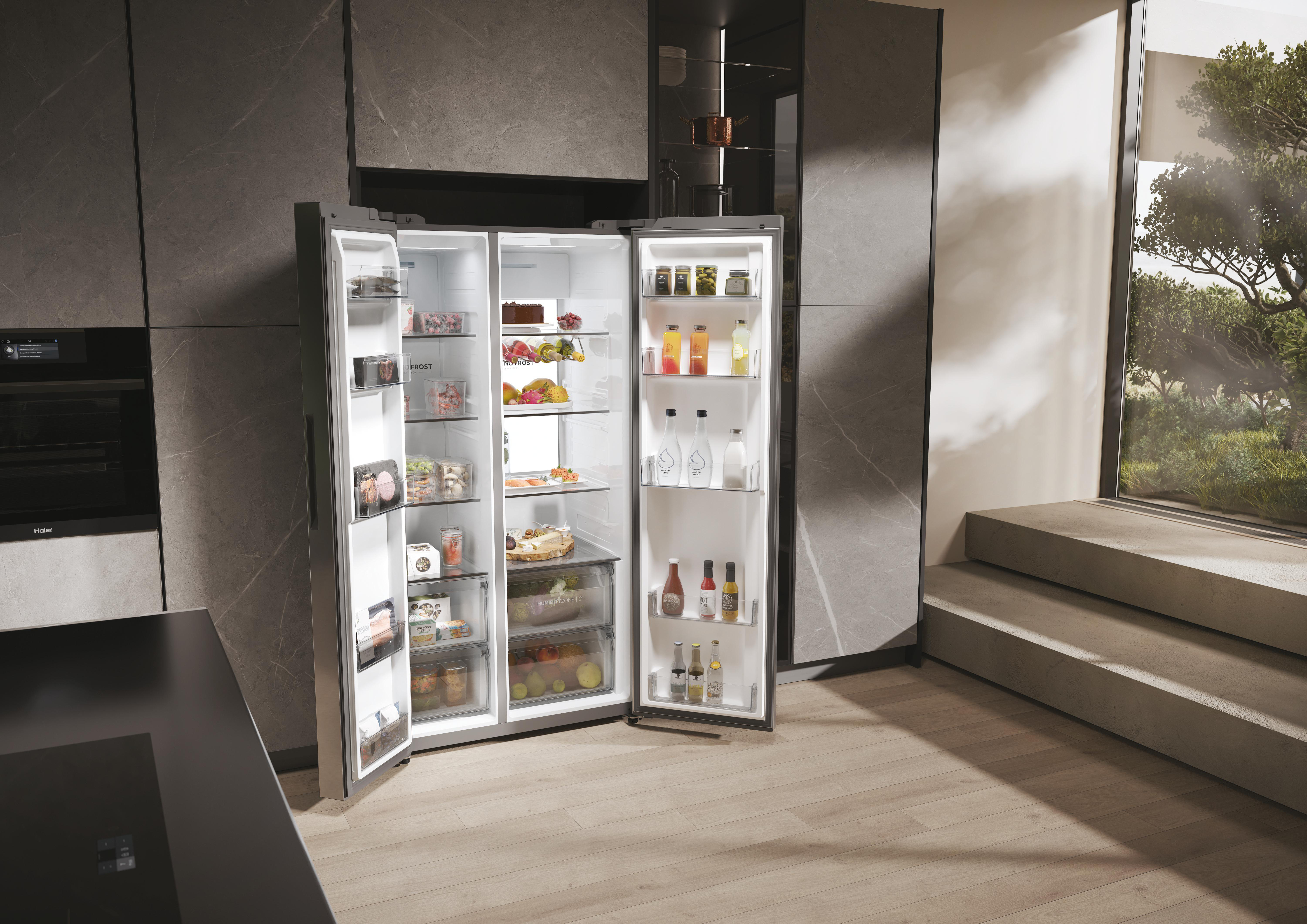 Offener Kühlschrank in moderner Küche. Gefüllt mit Lebensmitteln, Getränken und Früchten. Fenster mit Bäumen im Hintergrund. Holzboden.