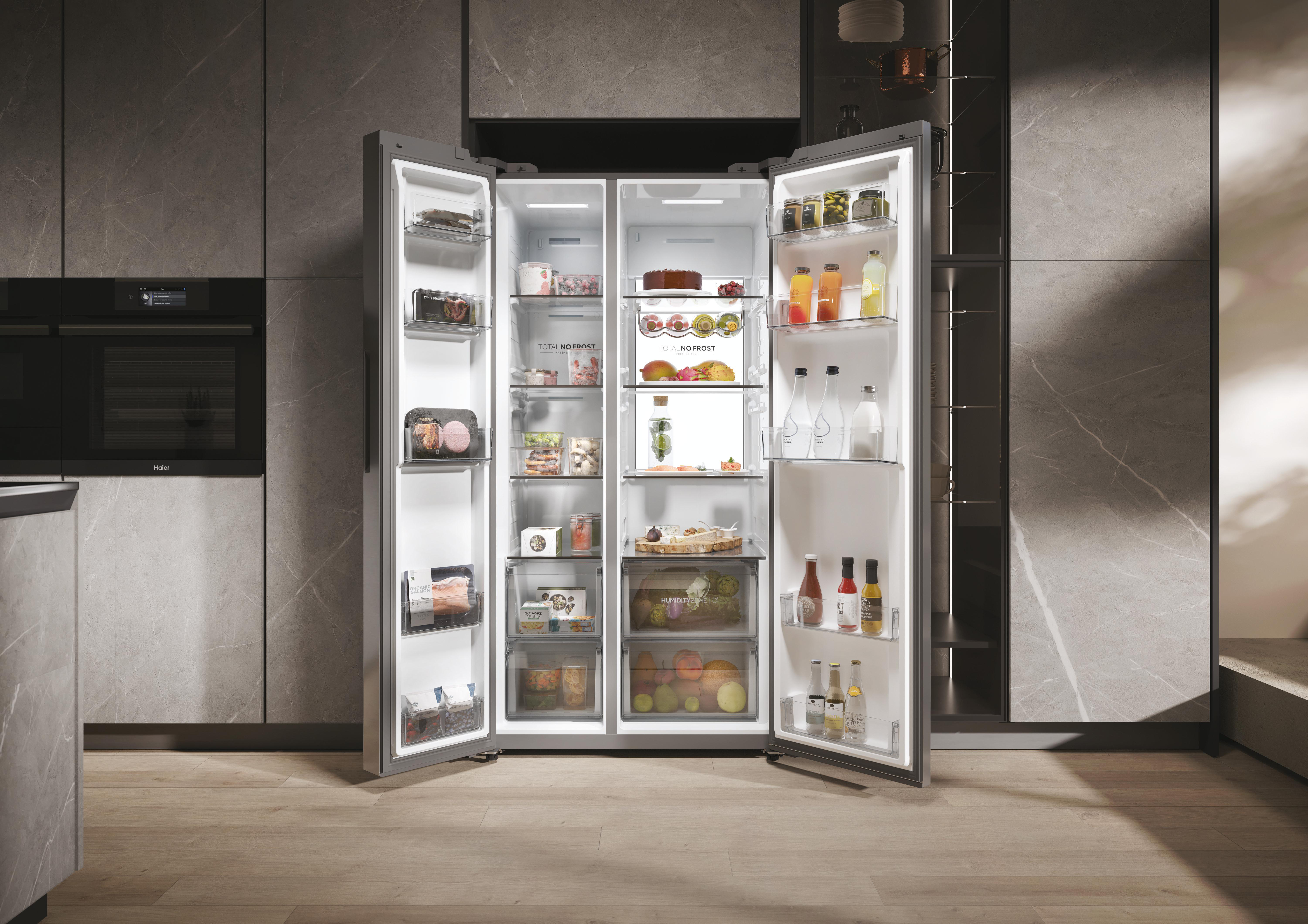 Offener Kühlschrank voller Essen. Es ist in einer modernen Küche. Graue Schränke und heller Holzboden.