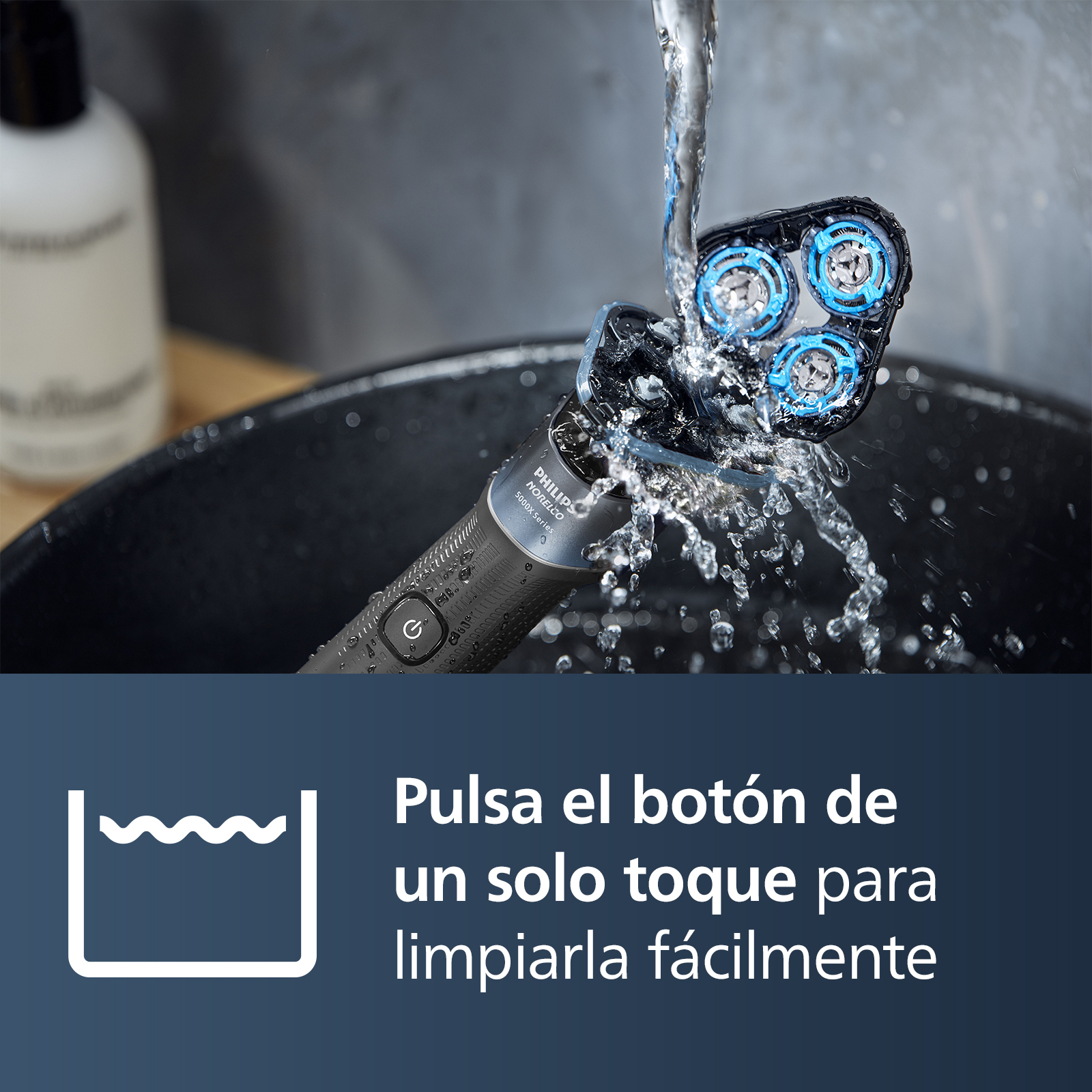Afeitadora eléctrica siendo limpiada con agua. El cabezal tiene detalles azules. Gotas de agua son visibles.