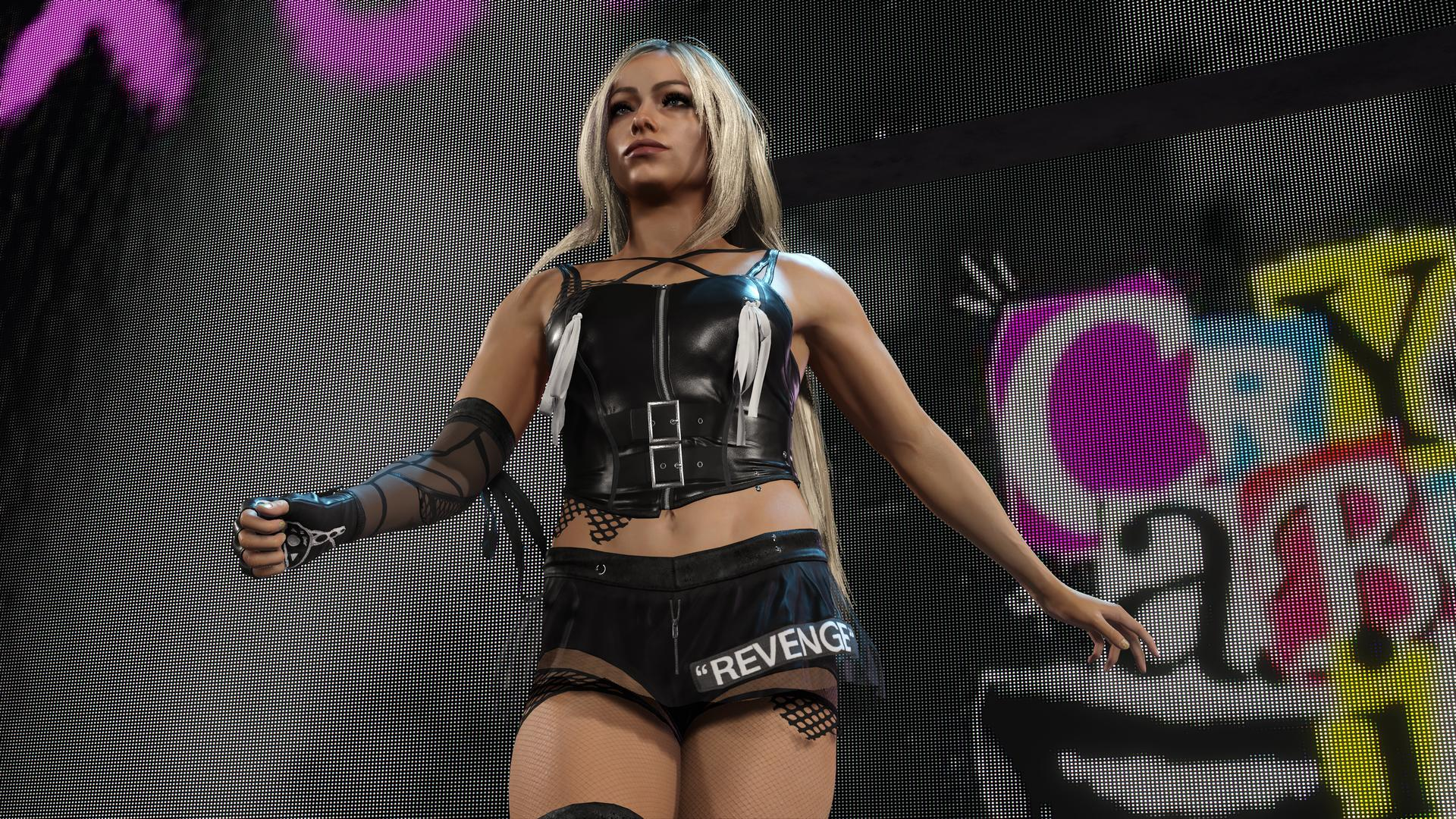 Wrestlerin in schwarzem Outfit mit 'REVENGE' auf der Shorts, steht auf einer Bühne.