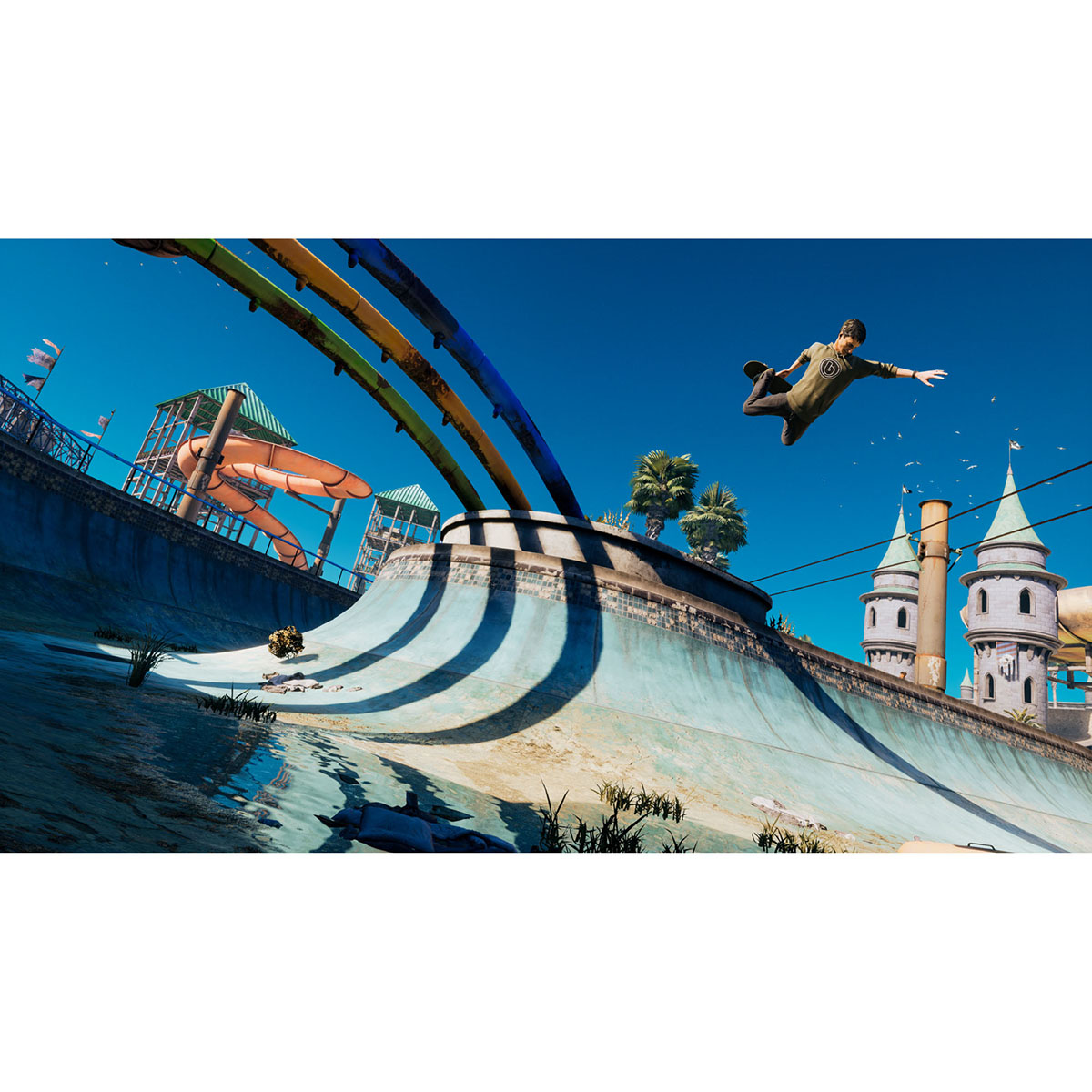 Una persona salta en el aire con una patineta sobre un halfpipe. Toboganes acuáticos y un castillo están en el fondo bajo un cielo azul.