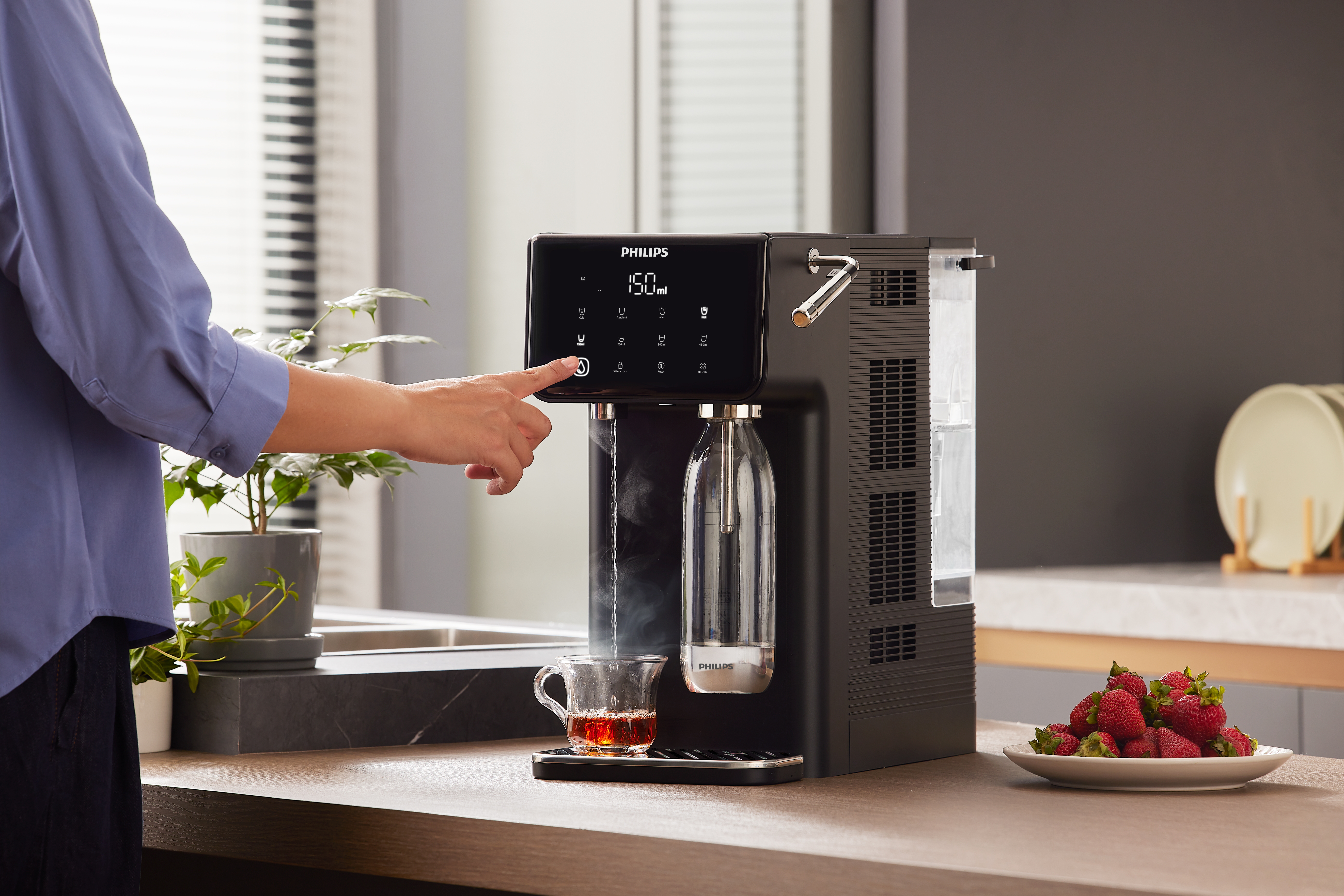 Osoba obsługuje czarny dystrybutor wody Philips, z parą.