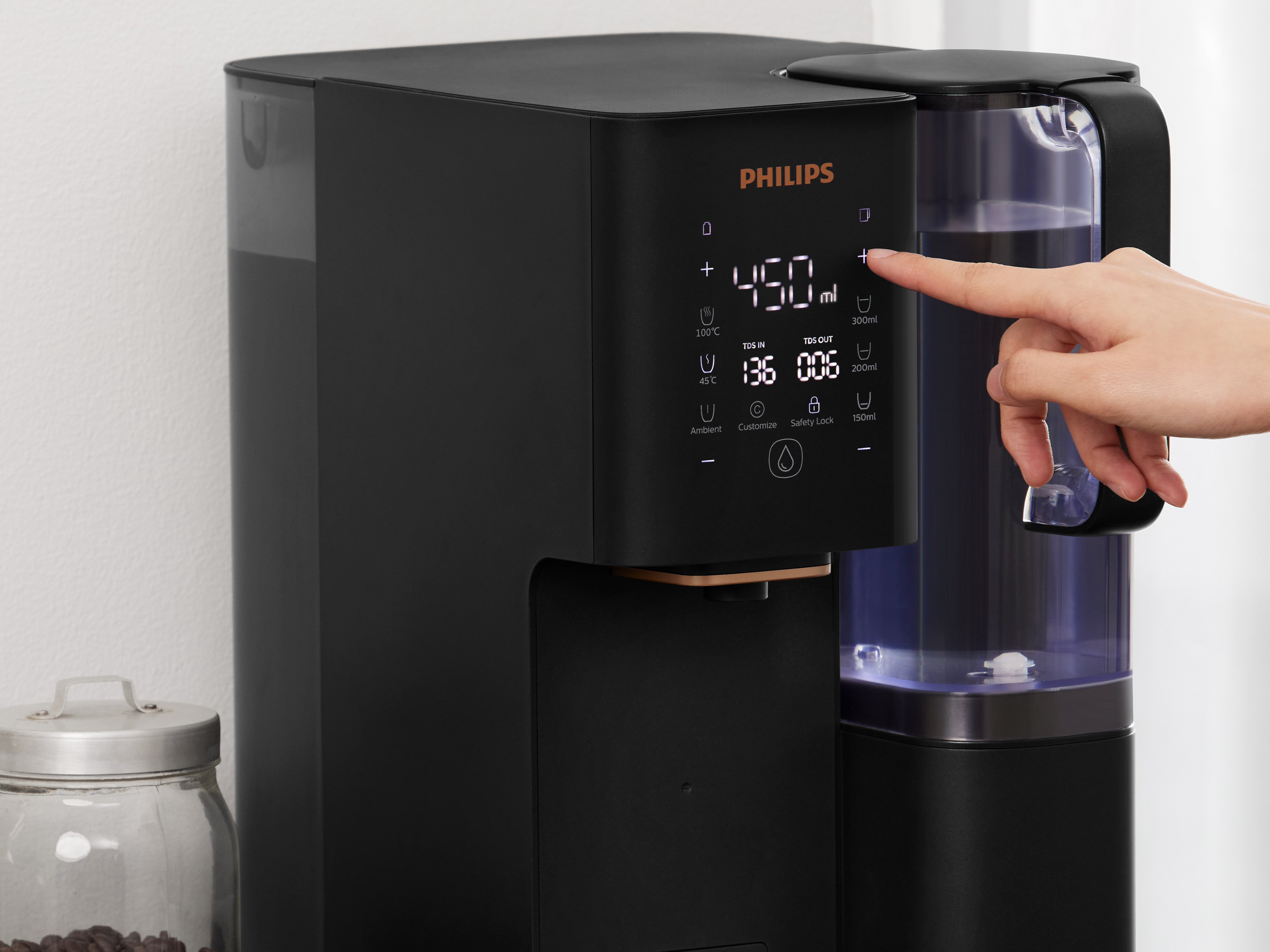 Ręka dotyka przycisku plus na ekranie dotykowym dystrybutora wody Philips, aby zwiększyć ilość wody.