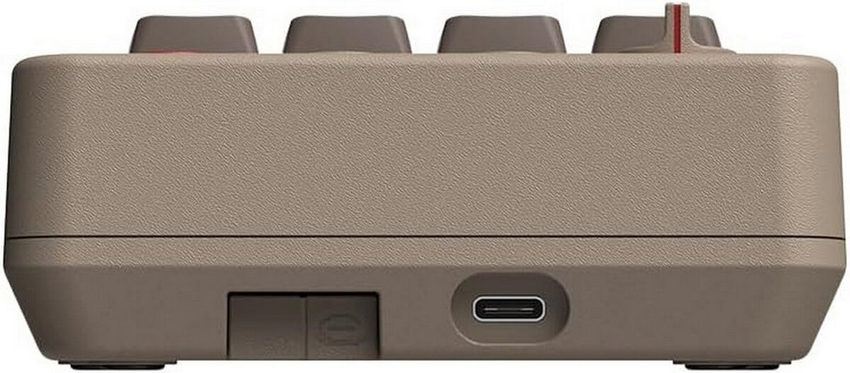 Bok klawiatury numerycznej retro z beżowymi i brązowymi klawiszami. Ma port USB-C i przełącznik. Jest beżowy.