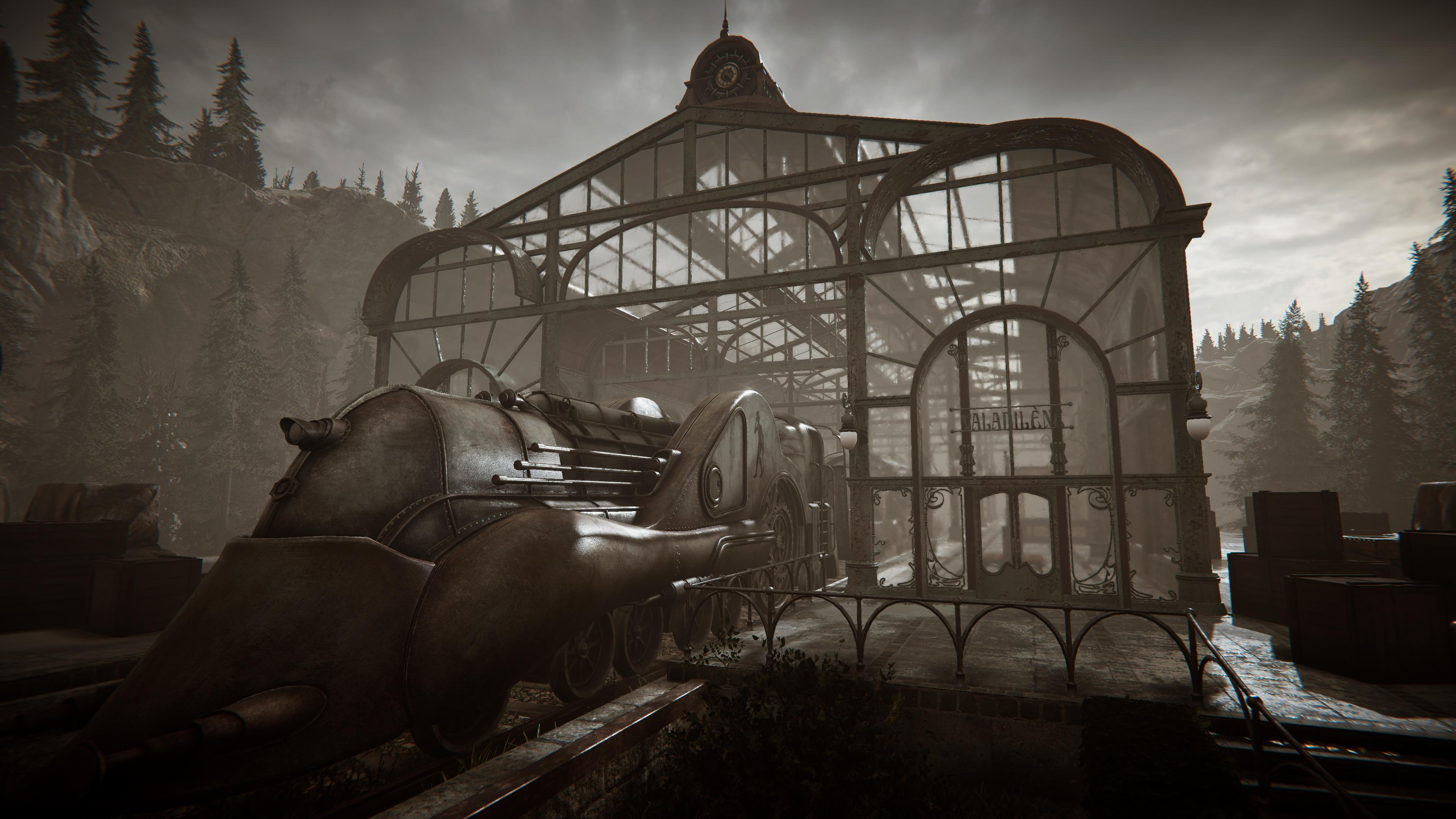 Stary budynek podobny do dworca kolejowego z pociągiem z przodu. Góry w tle.