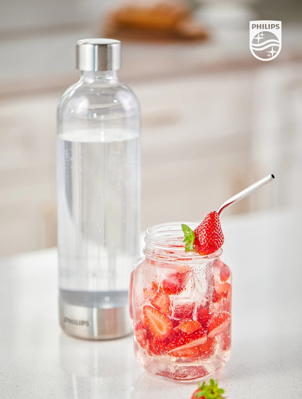 Szklana butelka z wodą i truskawkami, szklany słoik z truskawkami, słomka ze stali nierdzewnej.