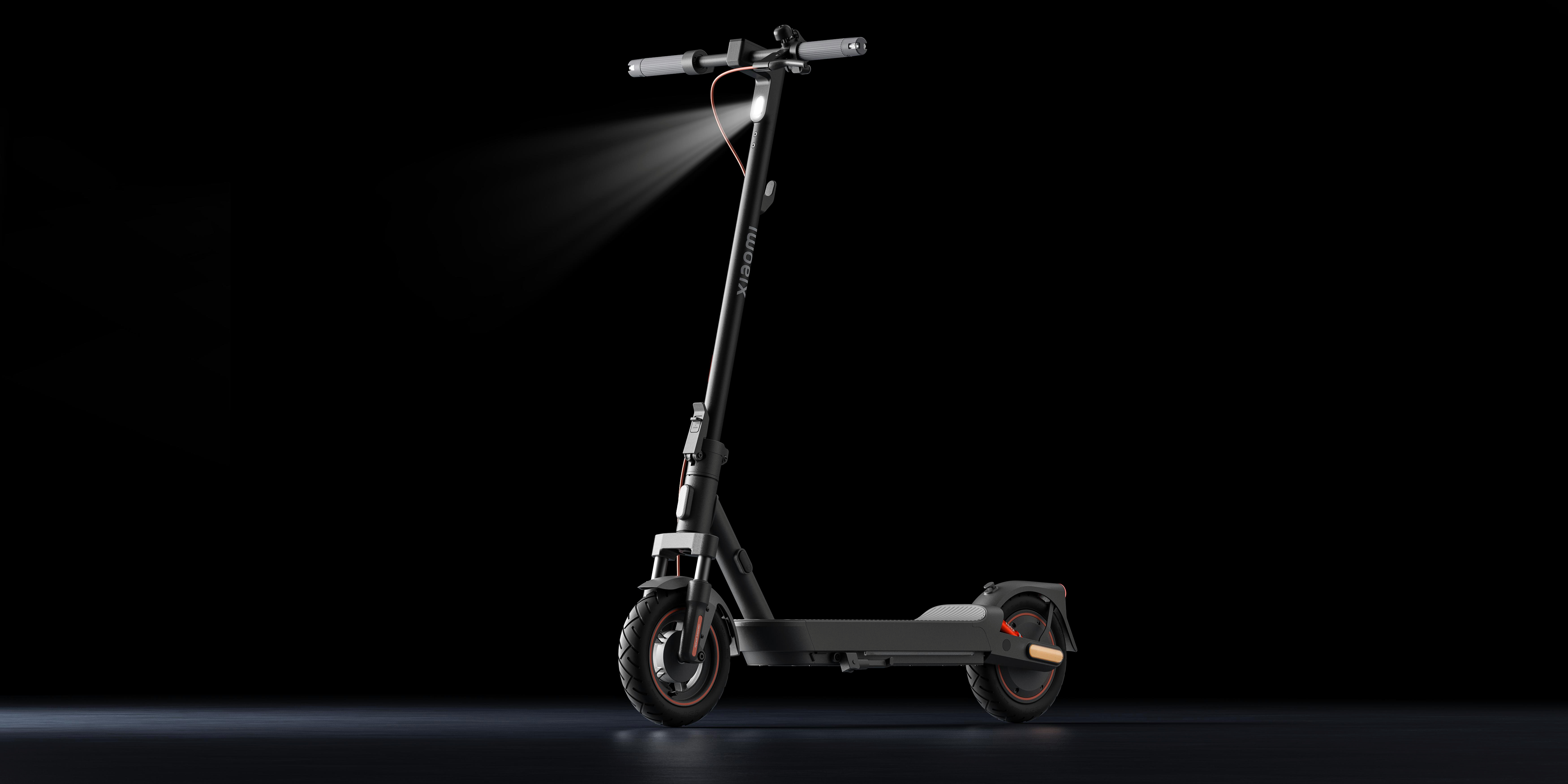 Schwarzer Elektroroller bei Nacht. Scheinwerfer an. Der Roller steht vor dunklem Hintergrund. Der Roller ist schwarz.