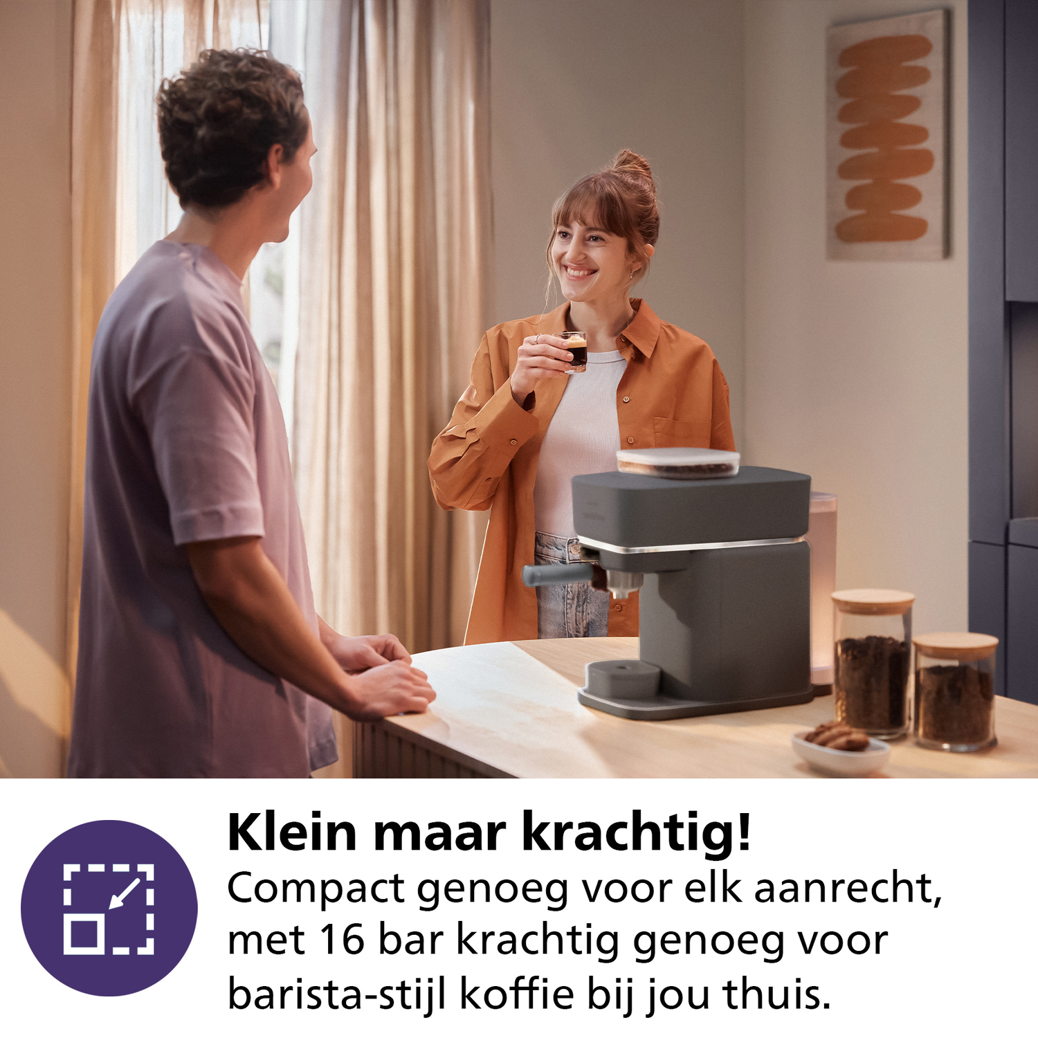 Man and woman in kitchen. Coffee machine on counter. Two jars of coffee beans. Smiling woman.