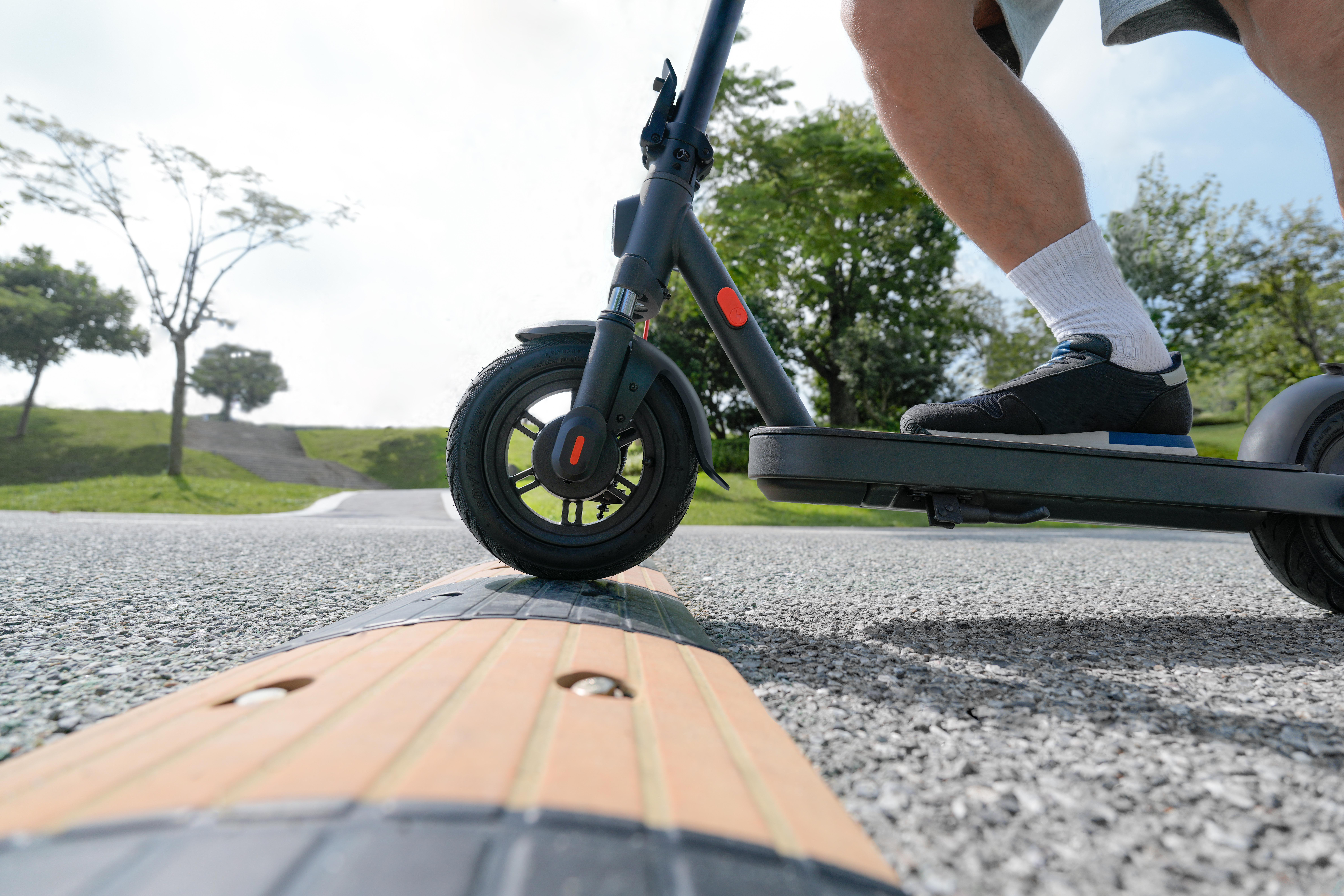 Person fährt mit einem Elektroroller auf einem Weg. Der Roller ist schwarz.