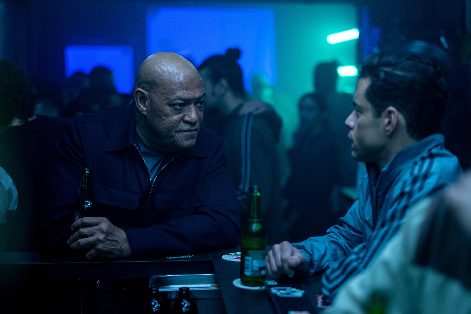Laurence Fishburne und Rami Malek in einer Bar. Sie sitzen und unterhalten sich.