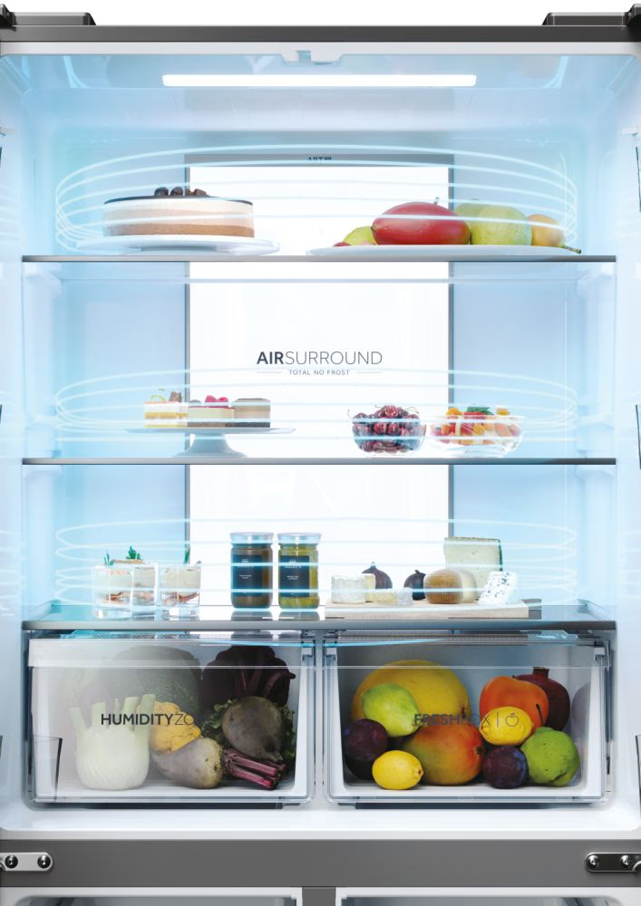 À l'intérieur du réfrigérateur Haier, gâteaux, fruits et fromage sont visibles, le système 'AIR SURROUND' est mis en évidence.