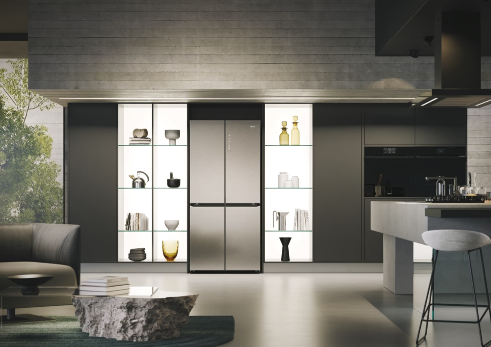 Un réfrigérateur Haier dans une cuisine moderne, flanqué d'étagères éclairées avec des objets de décoration.