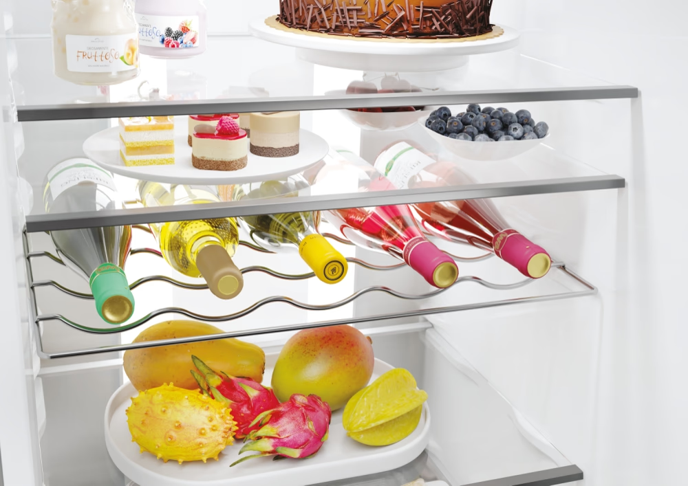 All'interno del frigorifero: bottiglie di vino, frutta e vari alimenti sugli scaffali.