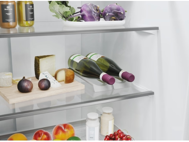À l'intérieur d'un réfrigérateur : du fromage, des figues, des bouteilles de vin et d'autres articles sur des étagères en verre.