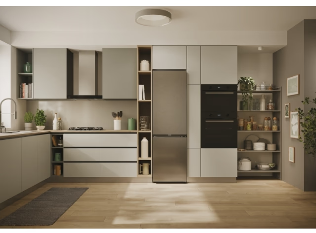 Cuisine avec réfrigérateur en acier inoxydable. Armoires, cuisinière et étagères visibles.