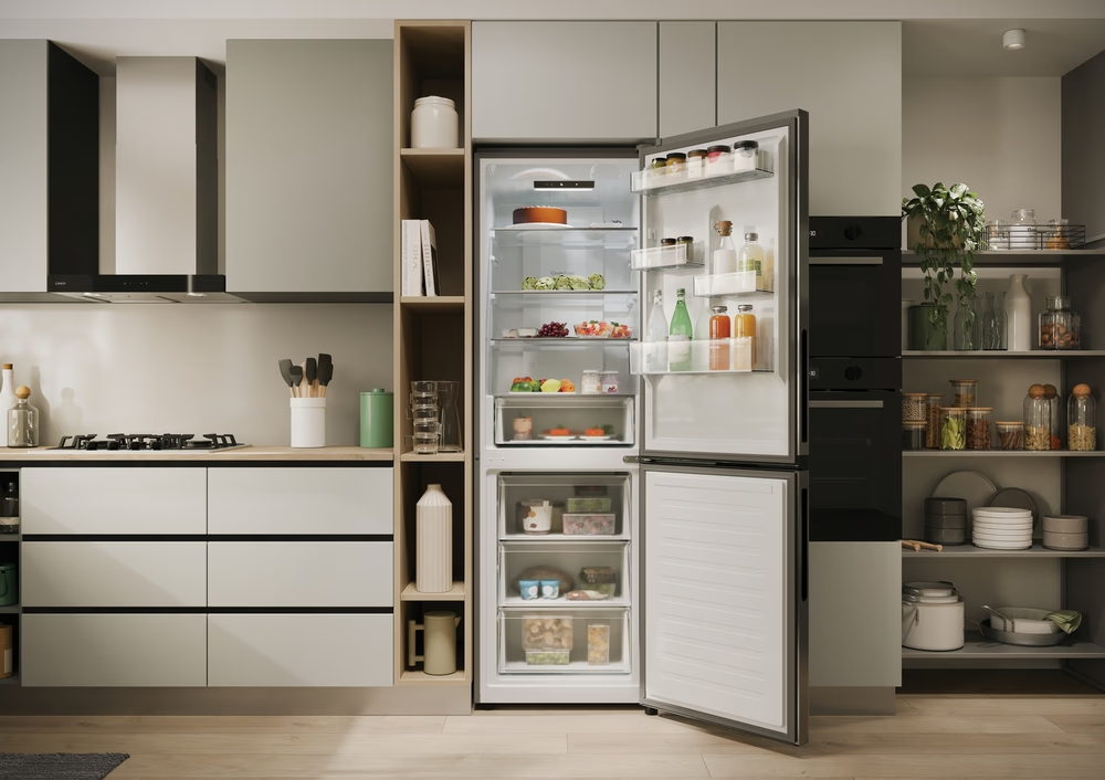 Küche mit offenem Kühlschrank. Innen sind Früchte, Flaschen und Regale sichtbar. Schubladen unten.