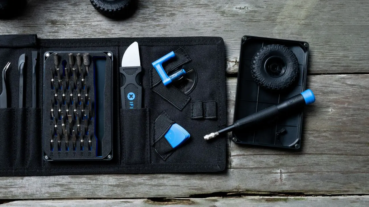 Des outils sont affichés sur une surface en bois, notamment des tournevis, une petite roue jouet et des outils de réparation.