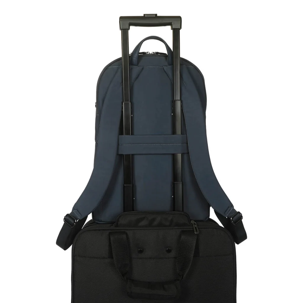 Mochila azul marino encima de una maleta con ruedas negra. La mochila tiene correas para el equipaje.