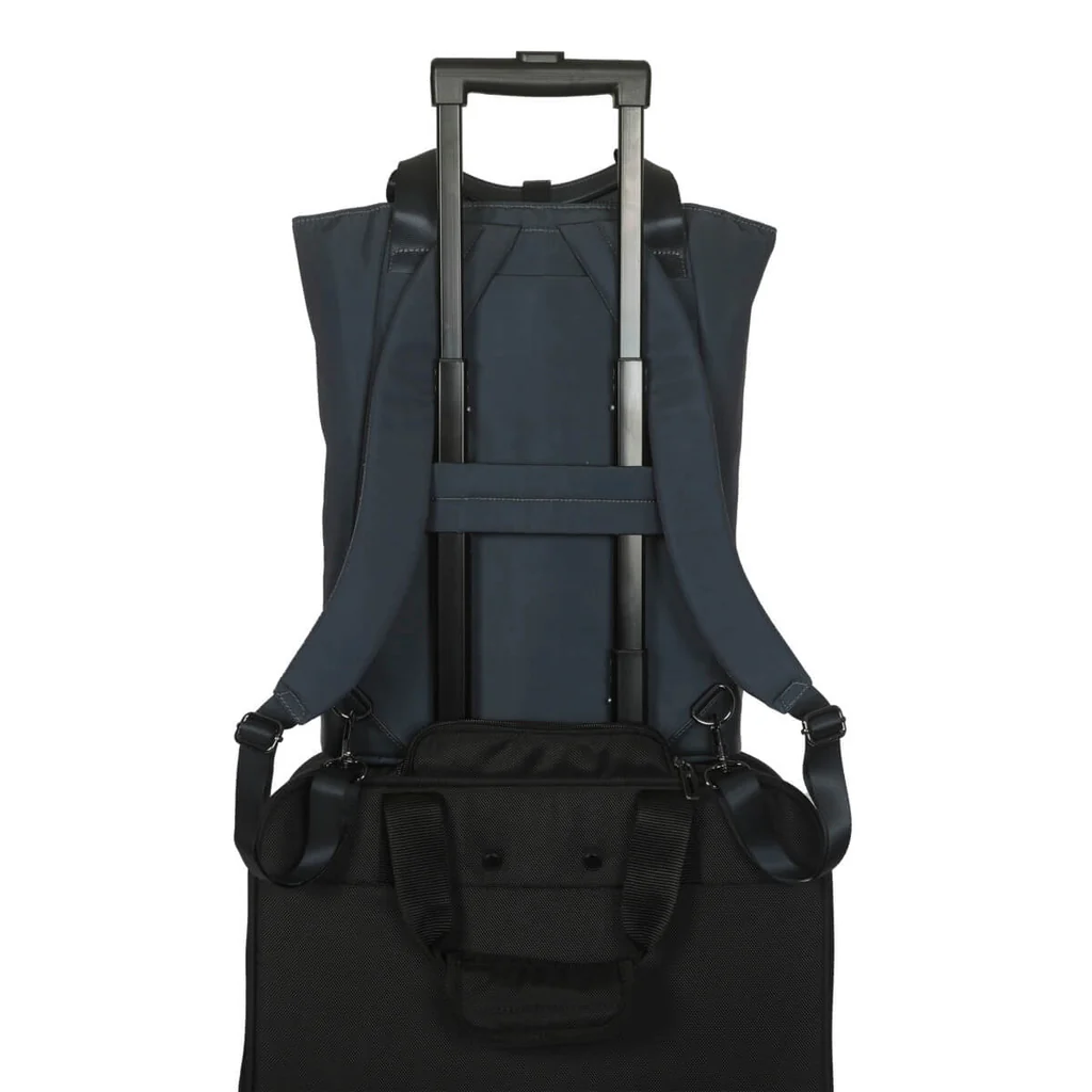 Bolso azul marino sobre maleta con ruedas, con correas de mochila y asa.