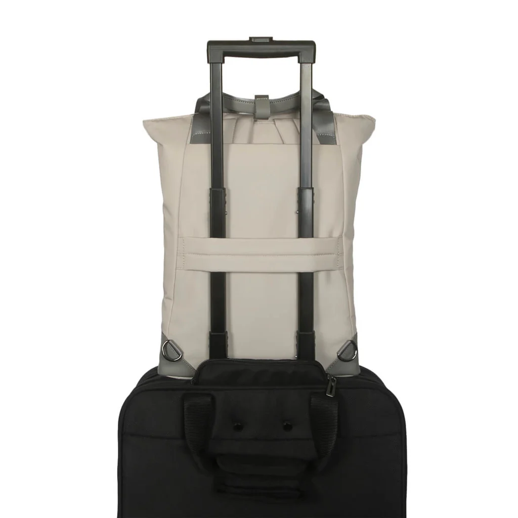 Una mochila beige claro sobre una maleta negra. Tiene un asa plateada.