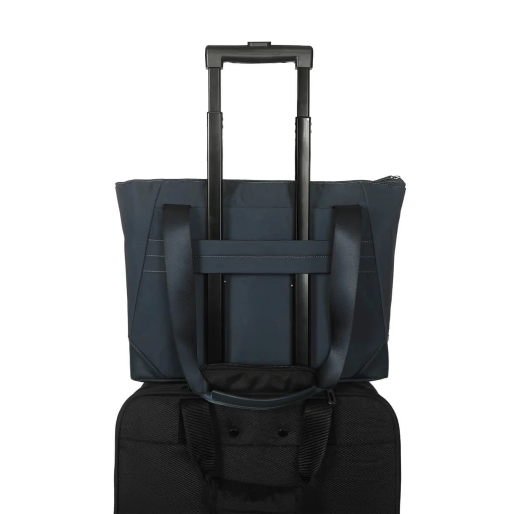 Bolso tote azul marino sobre una maleta negra. El asa está extendida.
