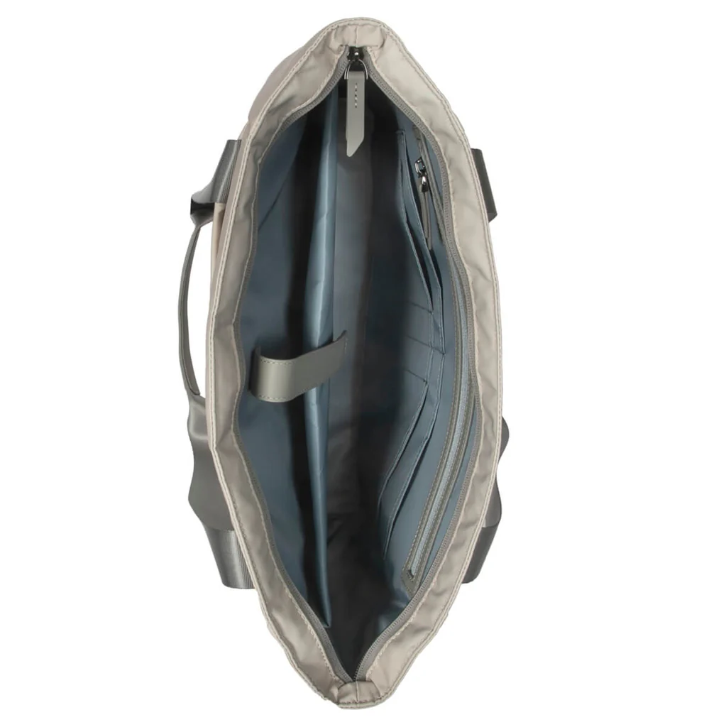 Vista interior de un bolso tote beige. Muestra un compartimento para portátil y múltiples bolsillos. Asas grises.