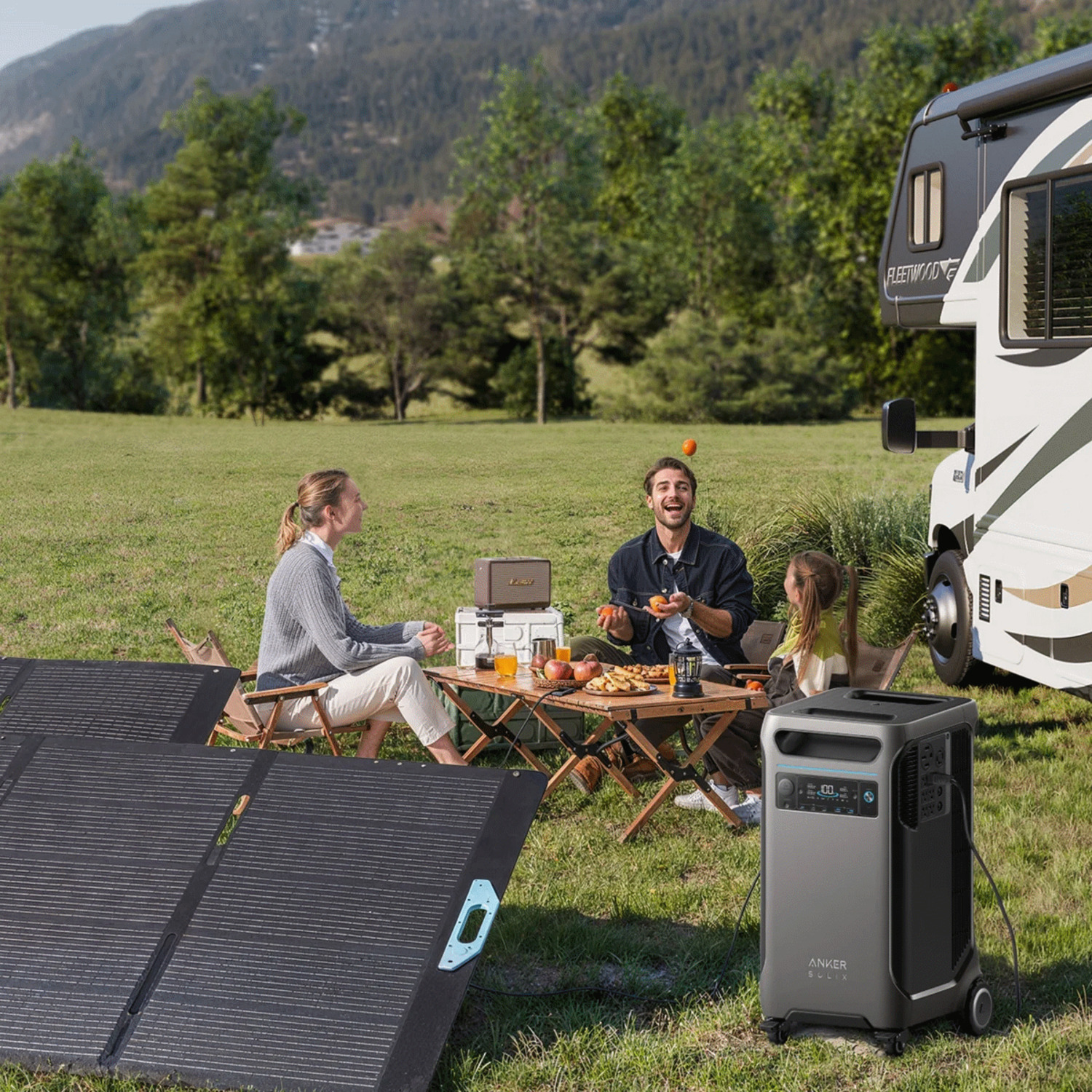 Camping familial près d'un camping-car. Ils sont assis à une table avec de la nourriture. Panneaux solaires au premier plan.