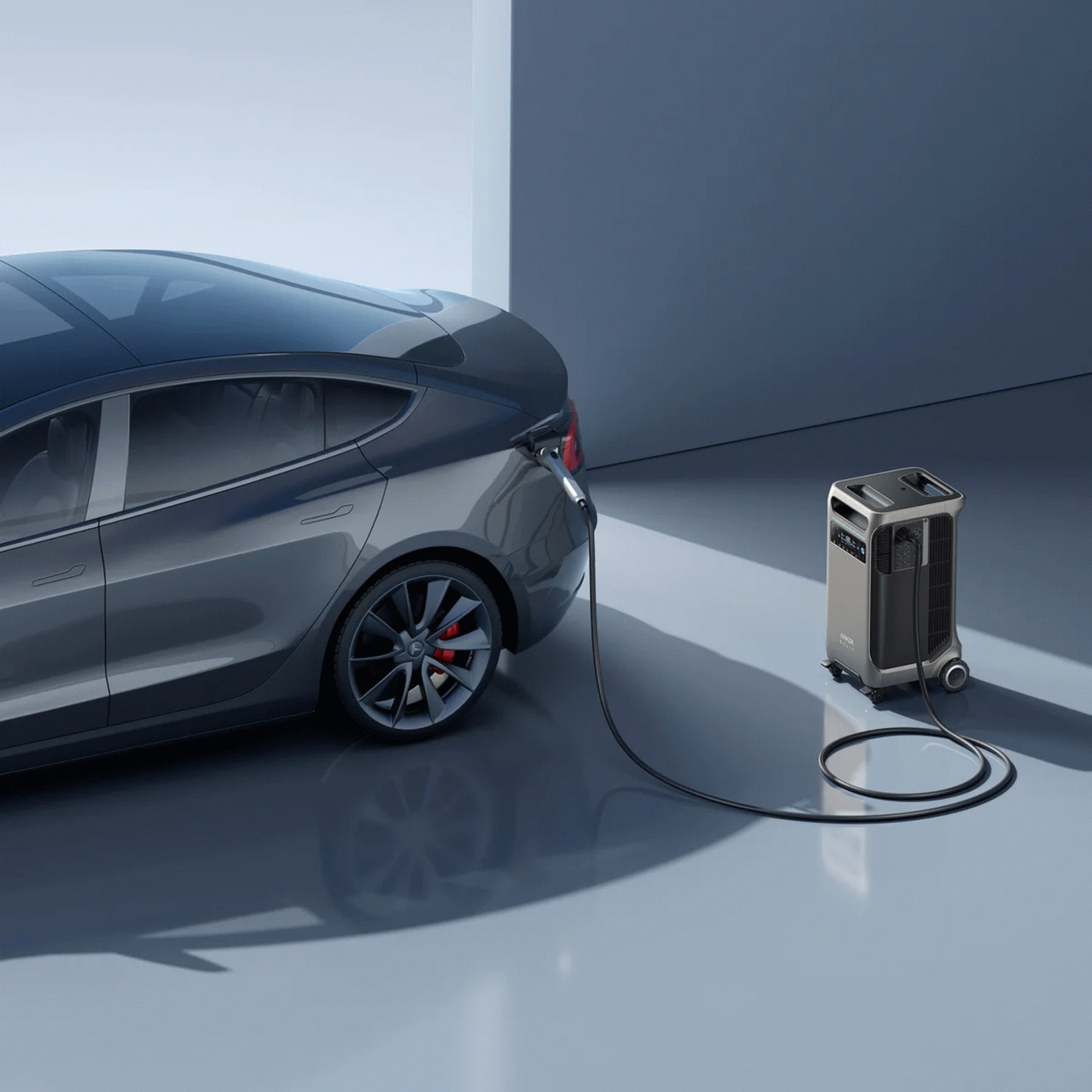 Une voiture grise se recharge à partir d'une station d'alimentation portable. La voiture est à gauche, la station à droite.